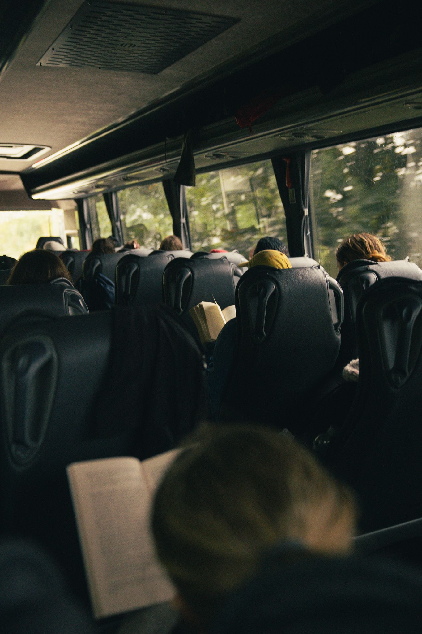Travelers reading on tour bus in Scottish highlands.