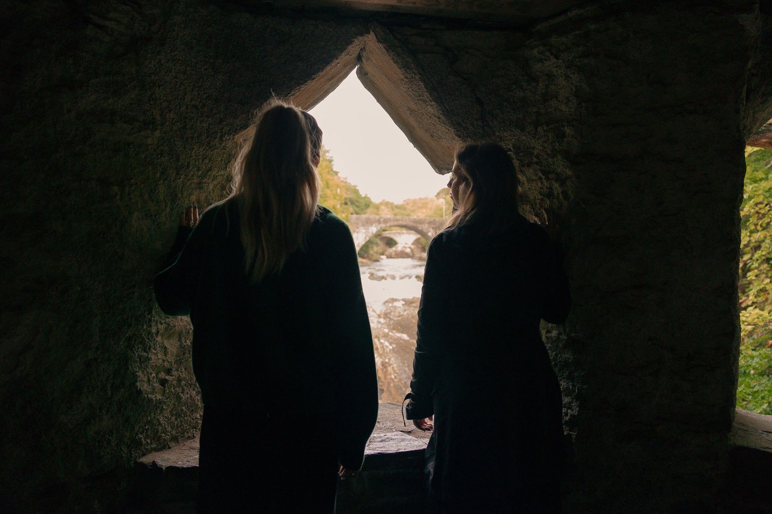 Girls looking out of stone structure near Invermoriston Falls, Scotland.