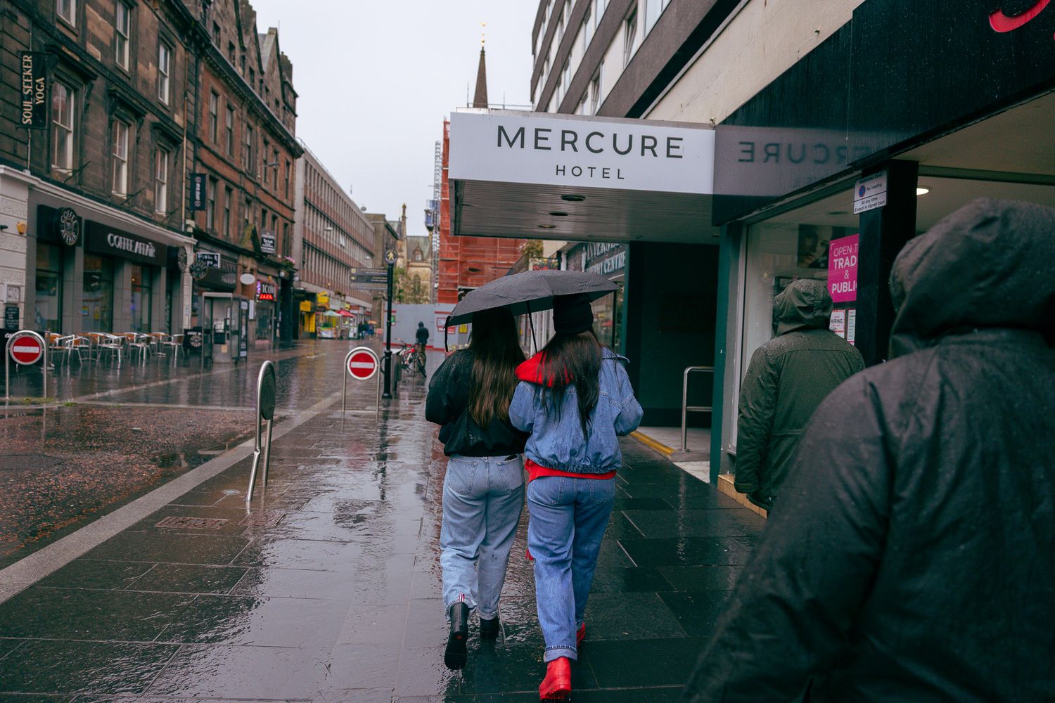 Girls walking in the rain outside Mercure Hotel in Inverness, Scotland.