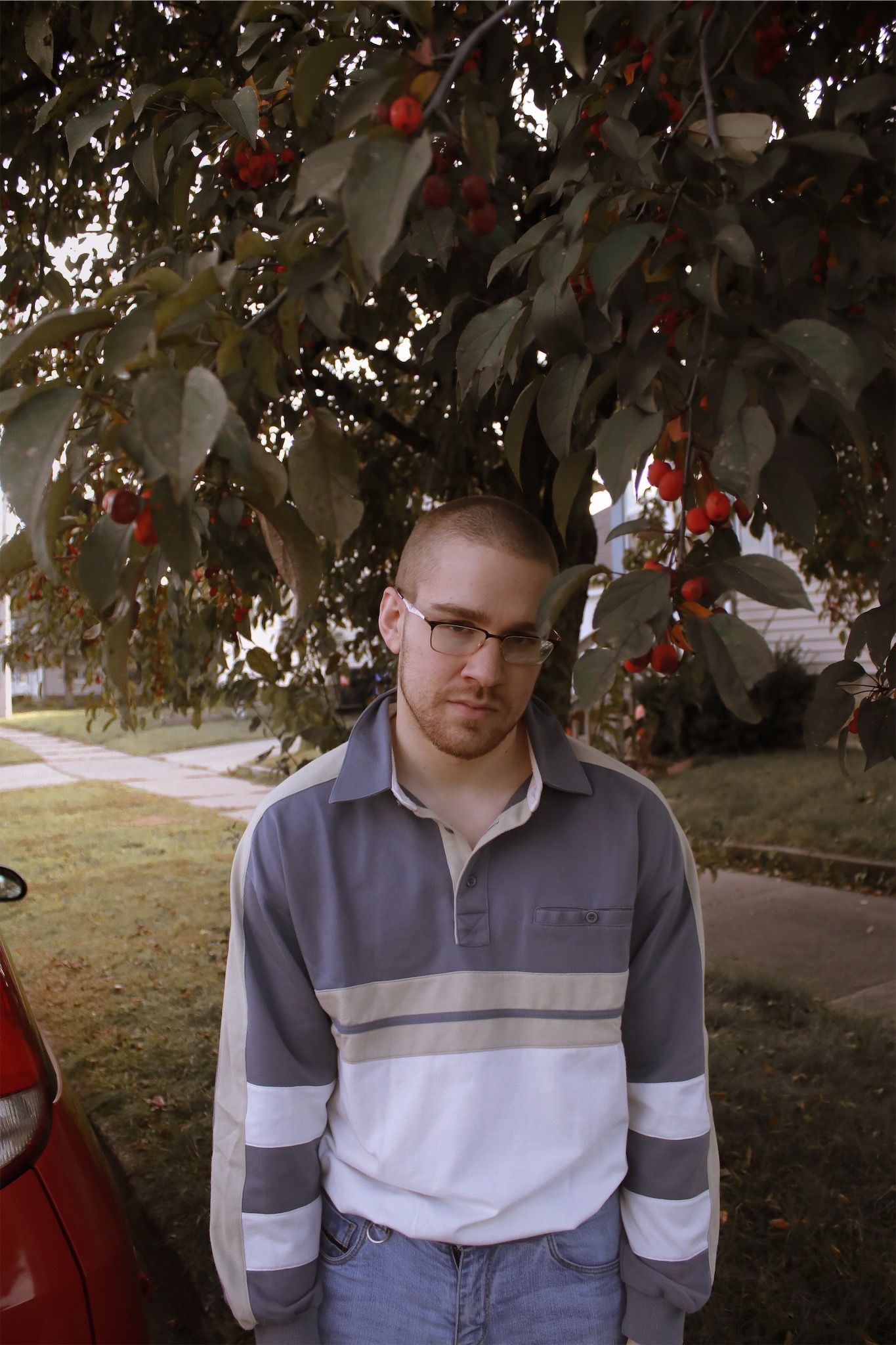 Man posing under tree on sidewalk.