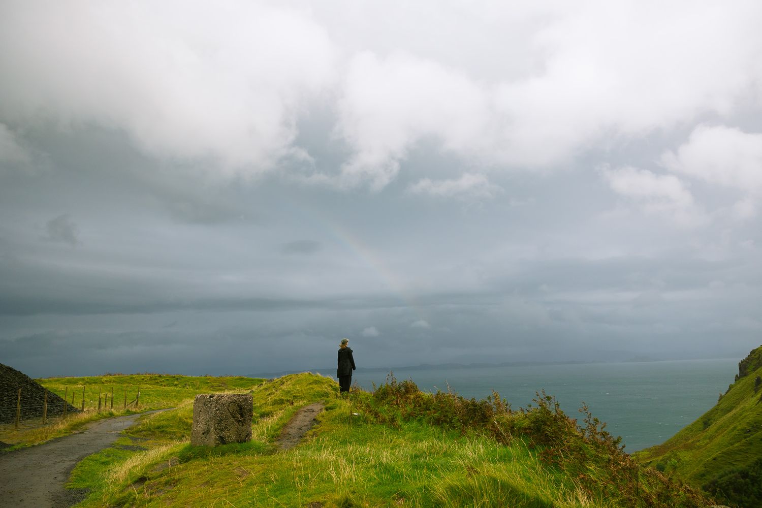 Girl looking at a rainbow at Lealt Falls in the Scottish Highlands.