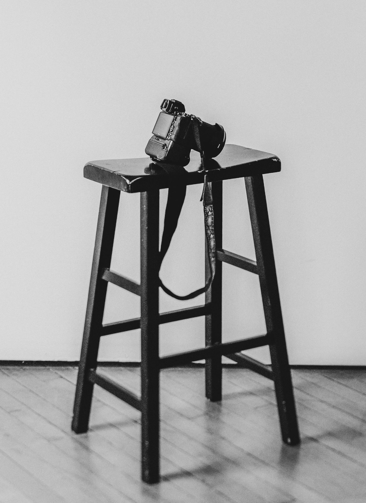 camera sitting on a black stool in front of a canvas backdrop in a portrait studio