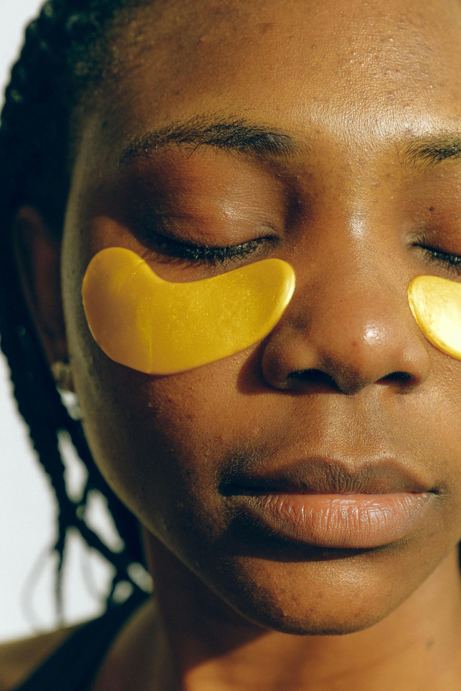 black woman with under eye treatment practicing self care