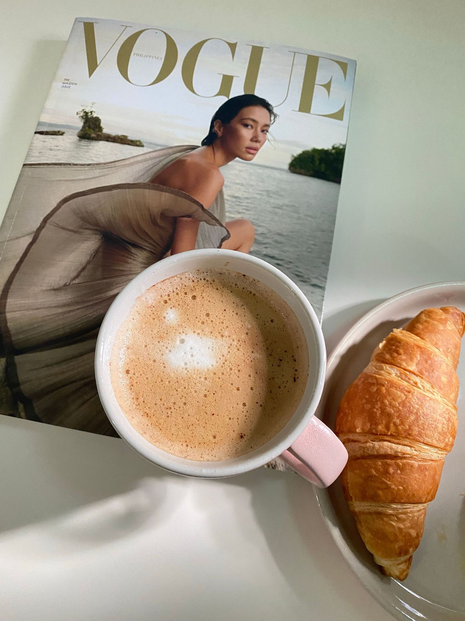 cup of coffee fashion magazine and croissant on a plate