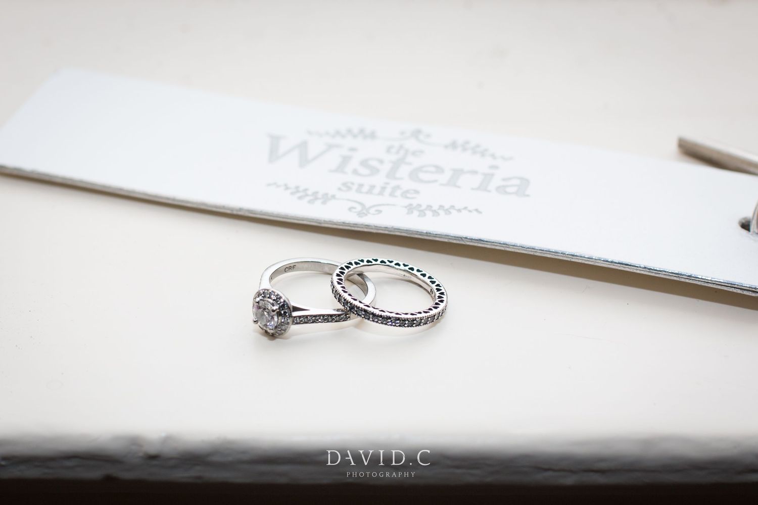 Silver diamond engagement ring and wedding band displayed on a Wisteria Suite card for a wedding.
