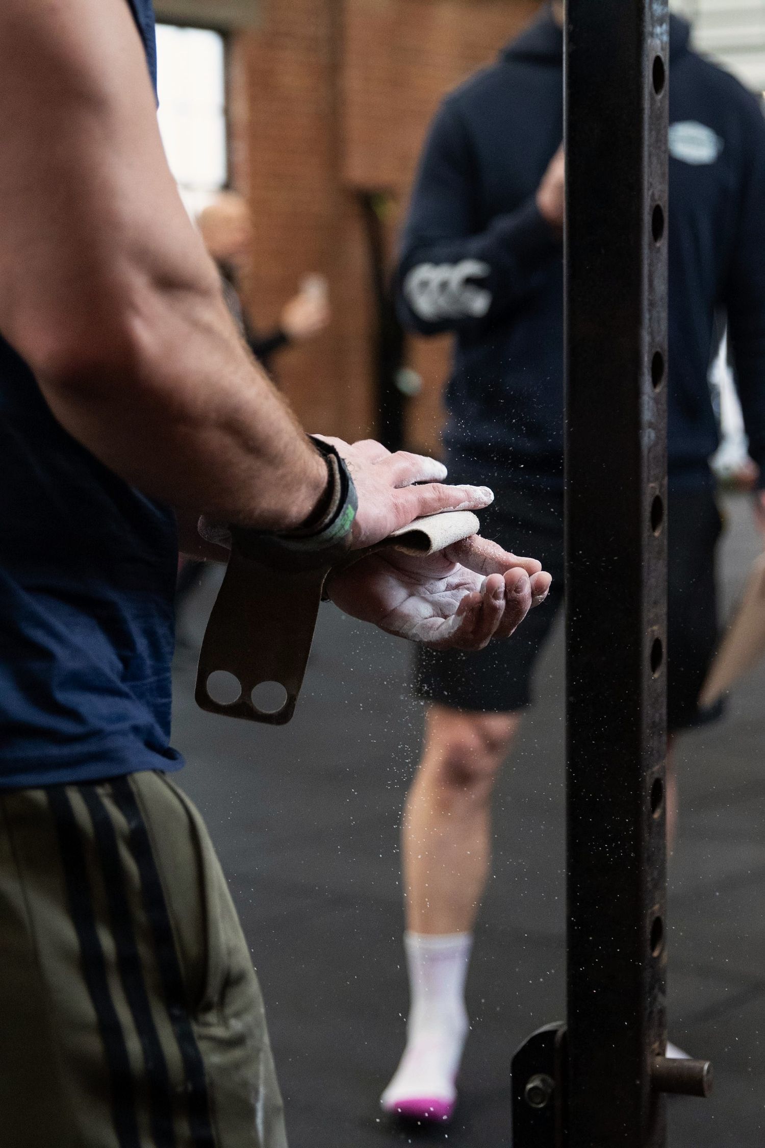 Fitness Photography - CrossFit athlete applying chalk to hands with gymnastic grips before a workout.