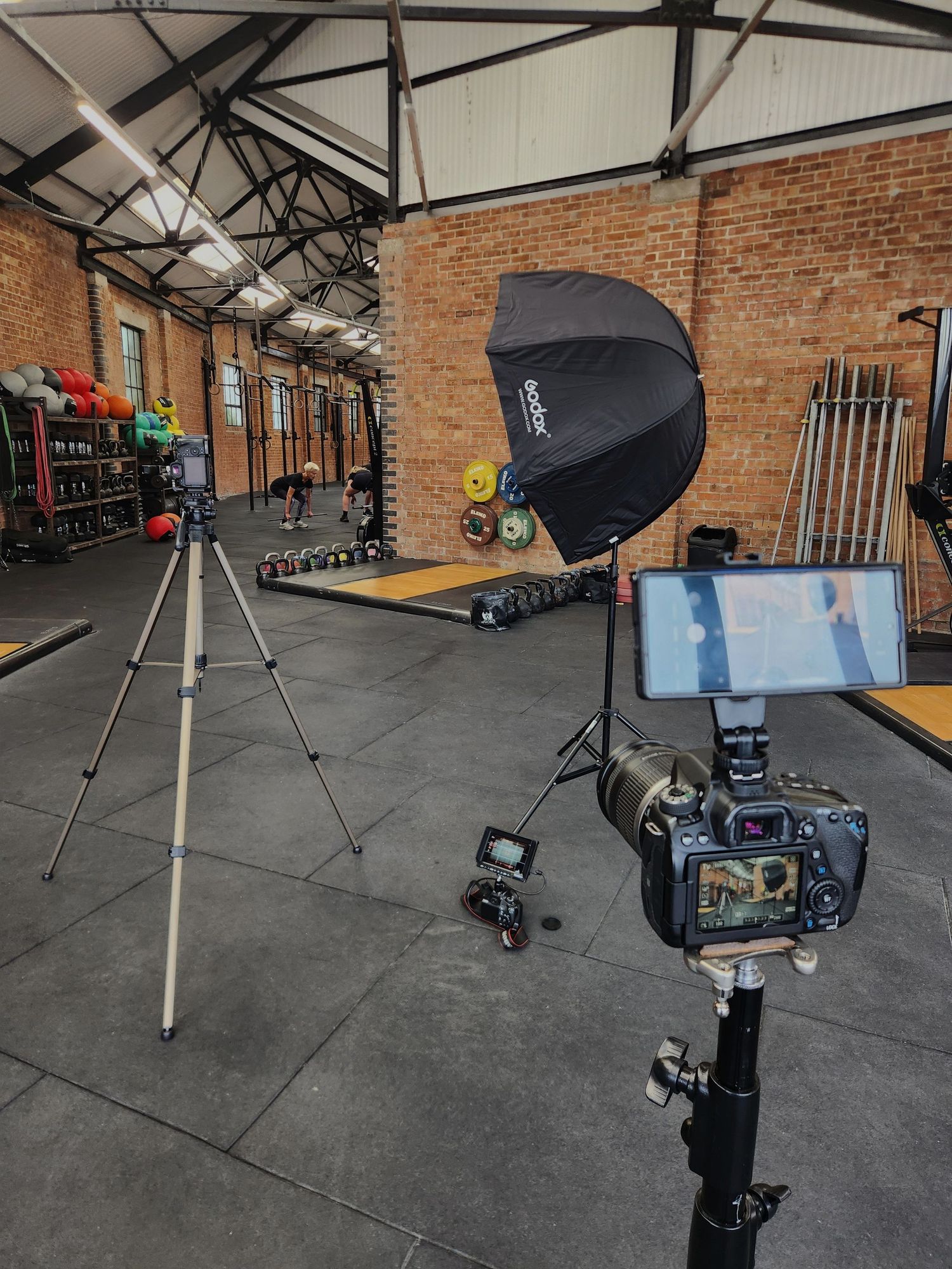 Studio Setup - Professional photography studio setup inside a brick gym with camera, tripod, and Godox softbox light.