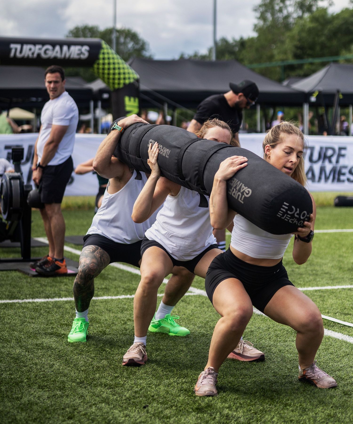 Sports Event Photography - Athletes carry a heavy sandbag together during a Turf Games outdoor fitness competition.