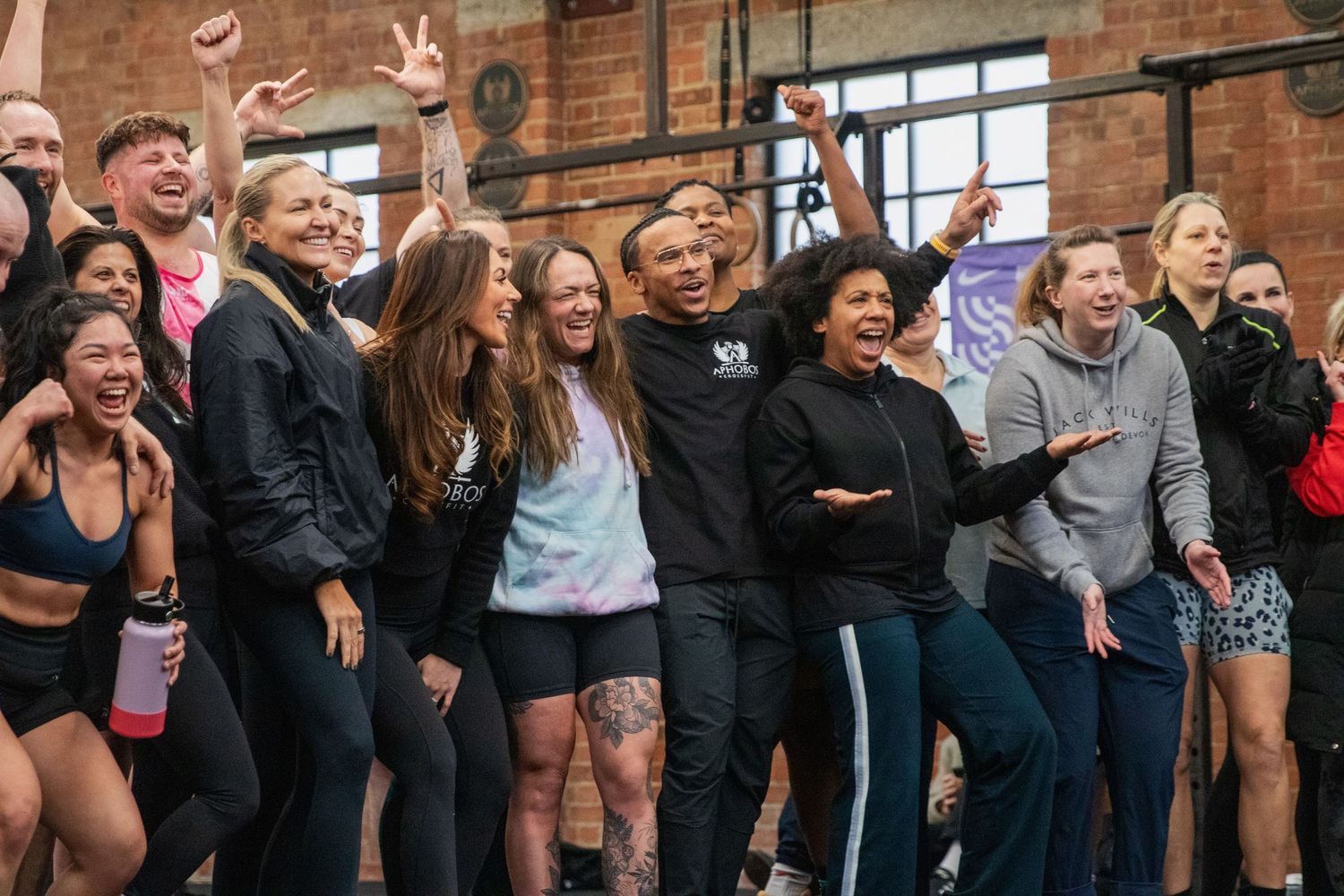 Excited group of CrossFit athletes celebrating together inside a brick gym.