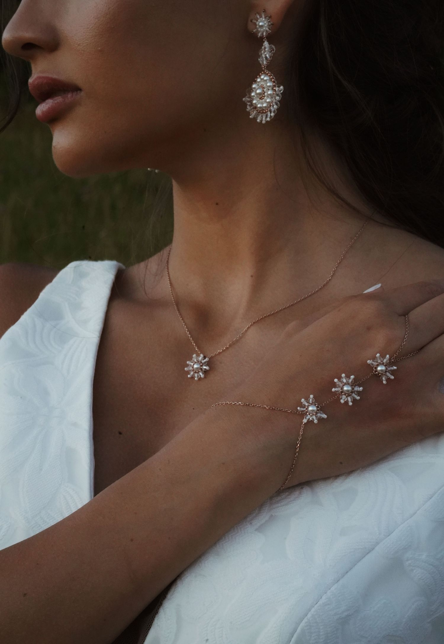 Close-up of delicate crystal jewelry including earrings and necklace on bride.