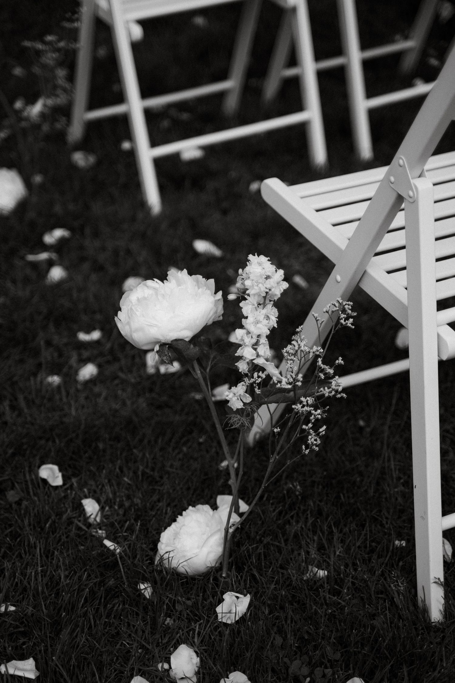 White garden chairs and delicate flowers create an intimate outdoor wedding setting.