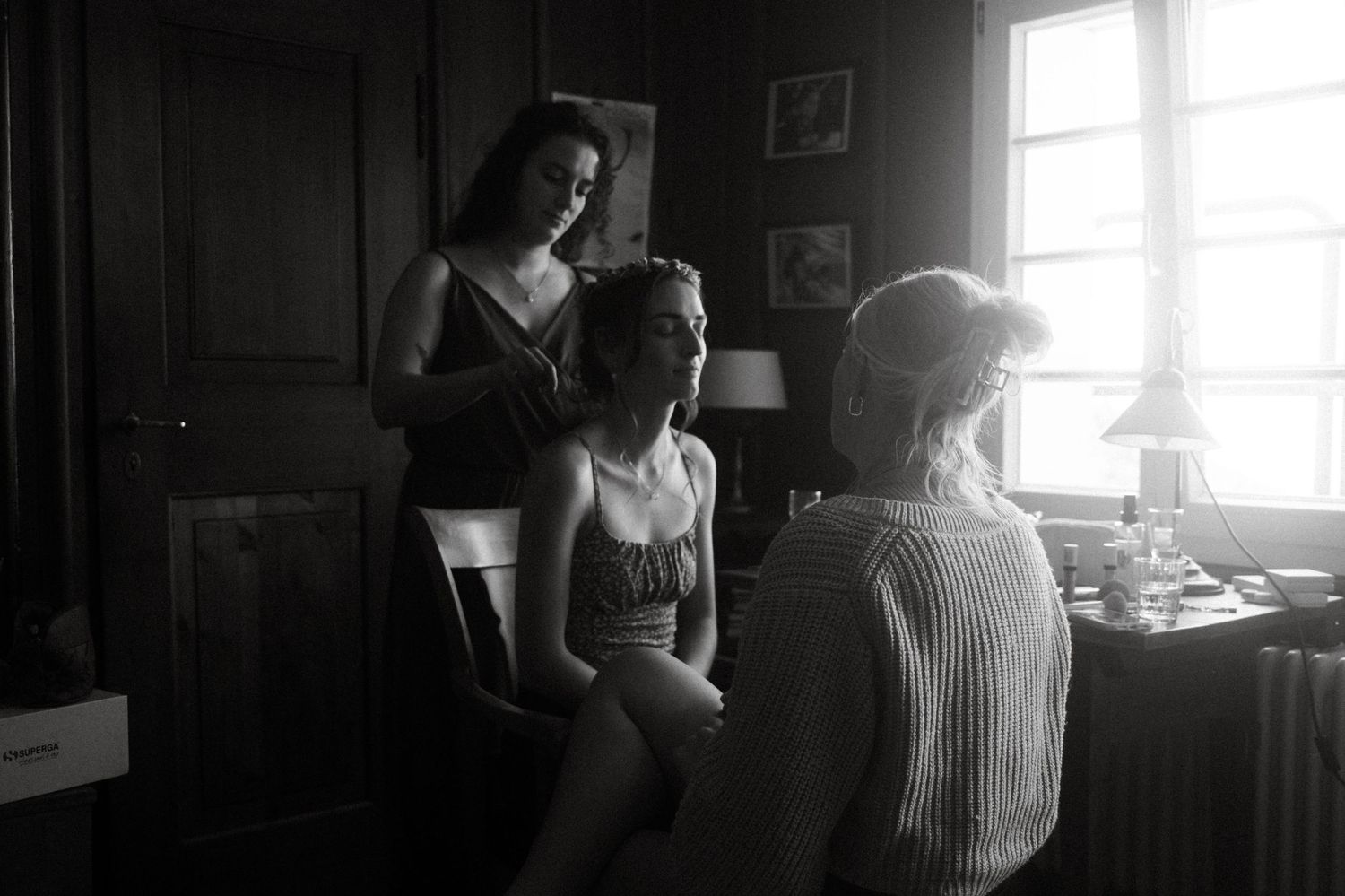 Black and white image showing wedding day preparations in a sunlit room.