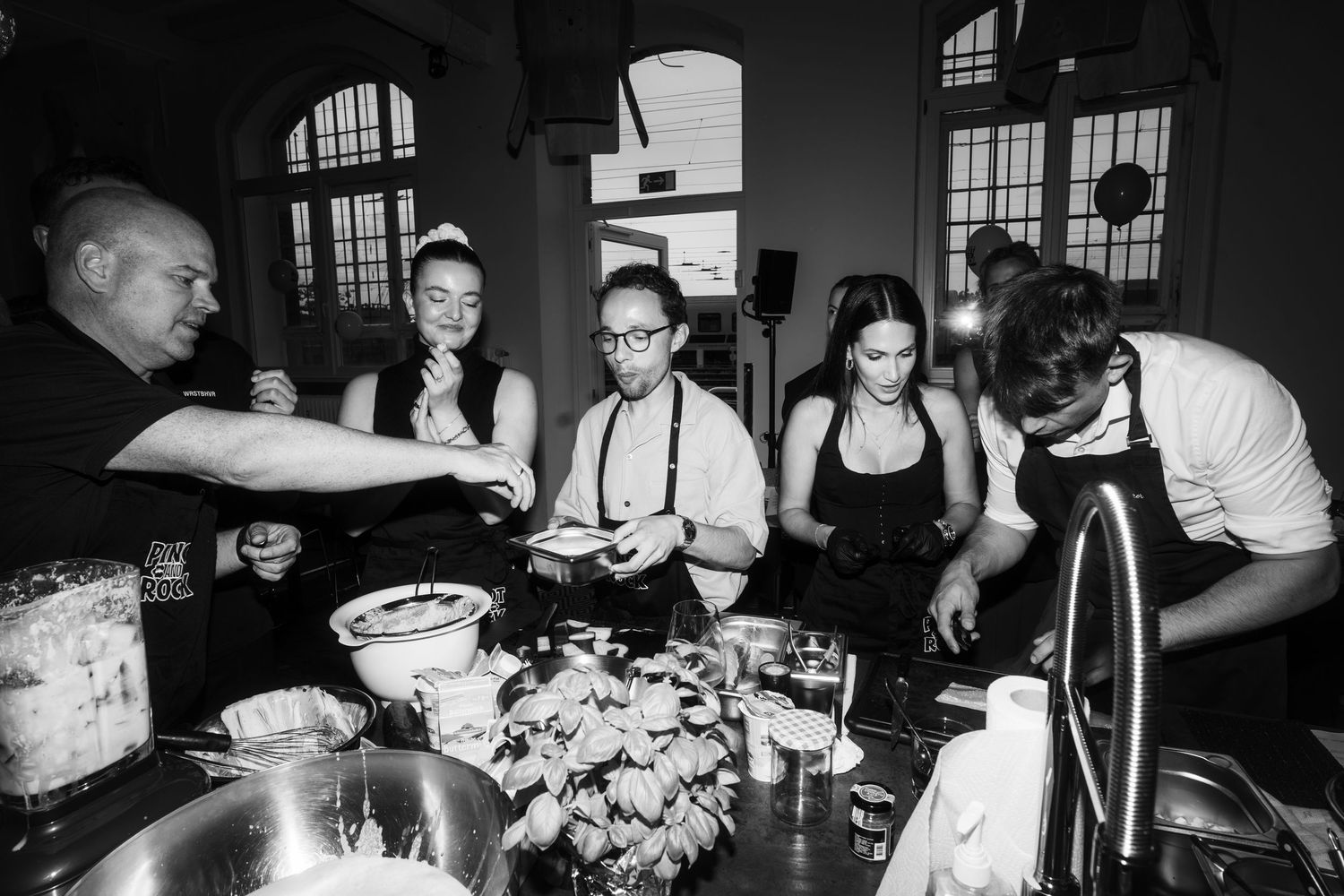 Group of people working together at a culinary station with ingredients and cooking supplies.