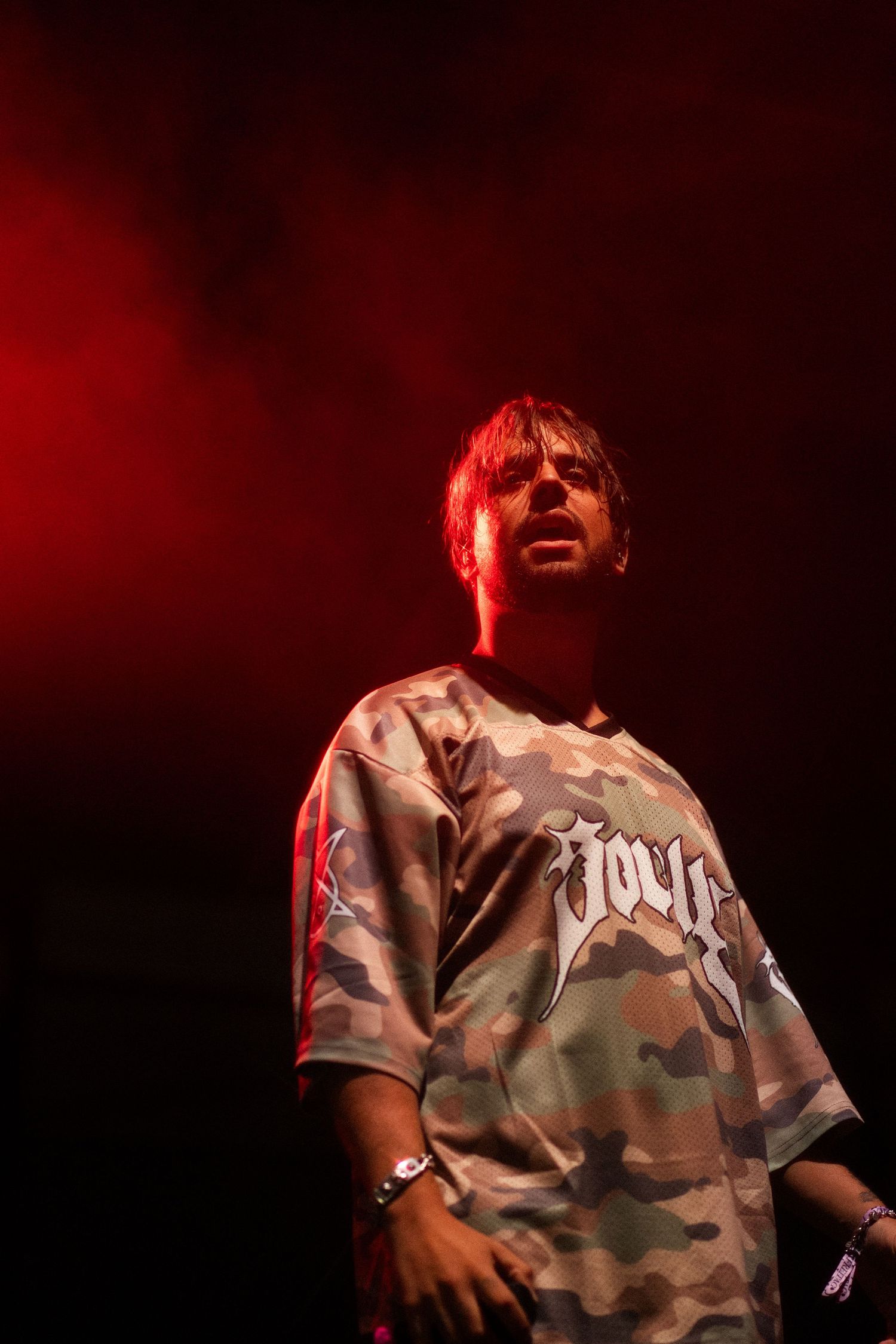 Singer Souly in camouflage shirt on stage under red lighting.
