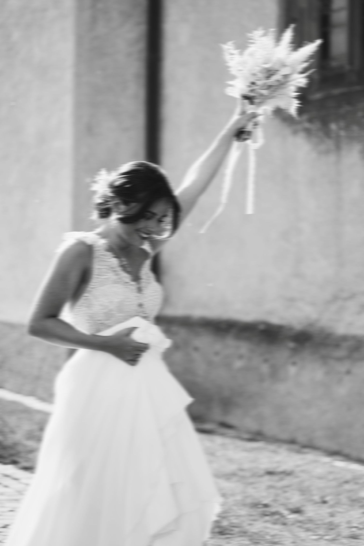 Black and white photo of a flowing wedding dress with raised bouquet.