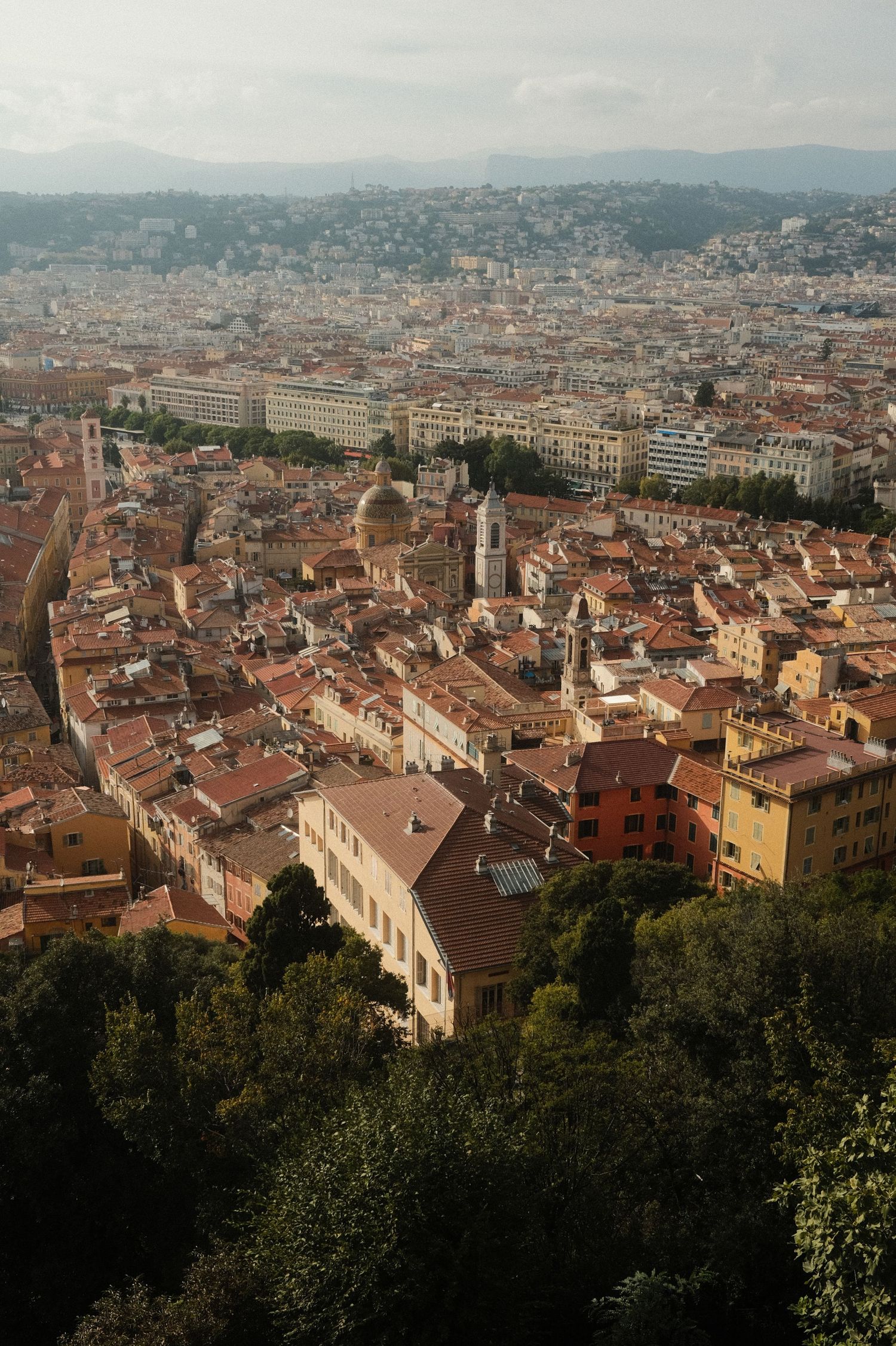 Panoramic aerial view of terracotta rooftops and architecture in a Mediterranean coastal city.