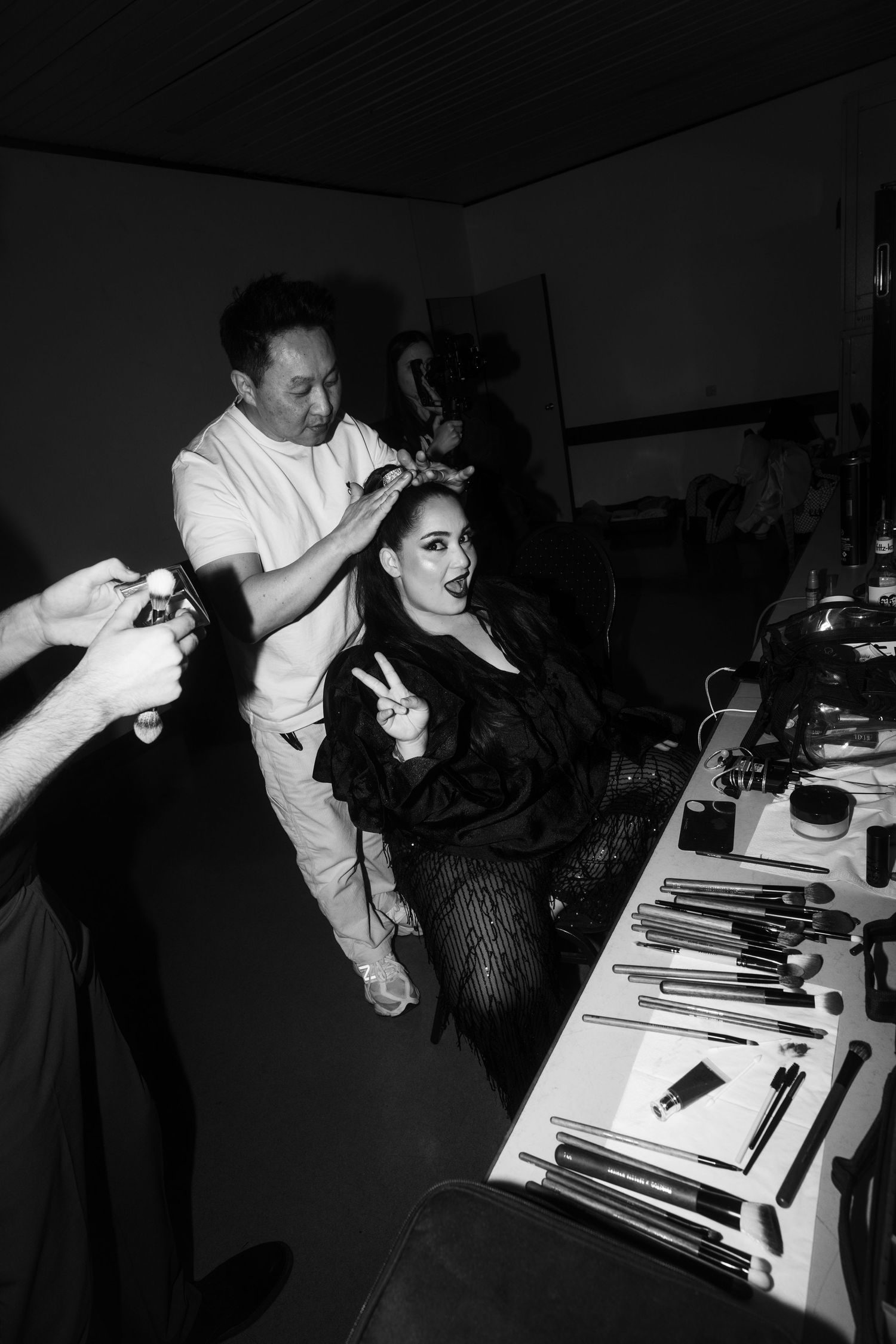 Black and white sequence showing preparation and styling work in a dimly lit room.