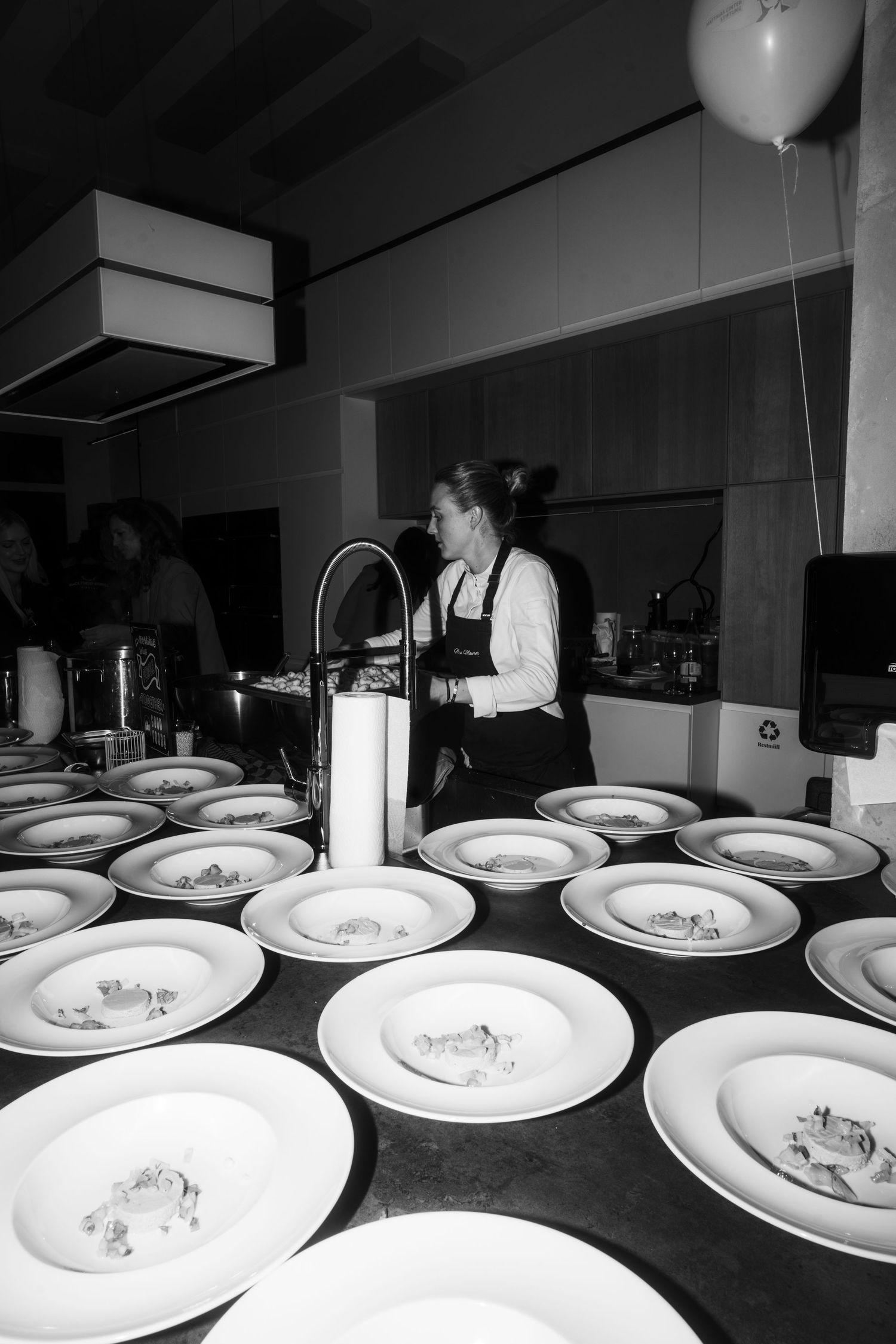 Chef preparing multiple plated dishes in a professional kitchen setting.