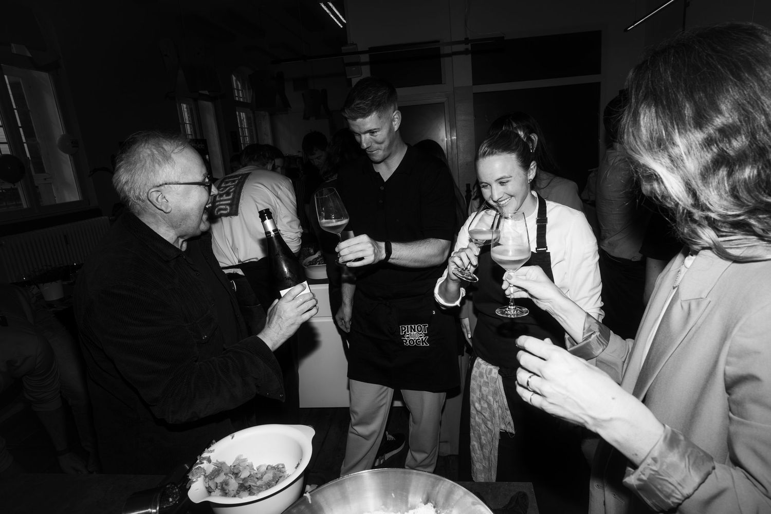 Black and white candid shot of group sharing drinks and food at informal gathering.