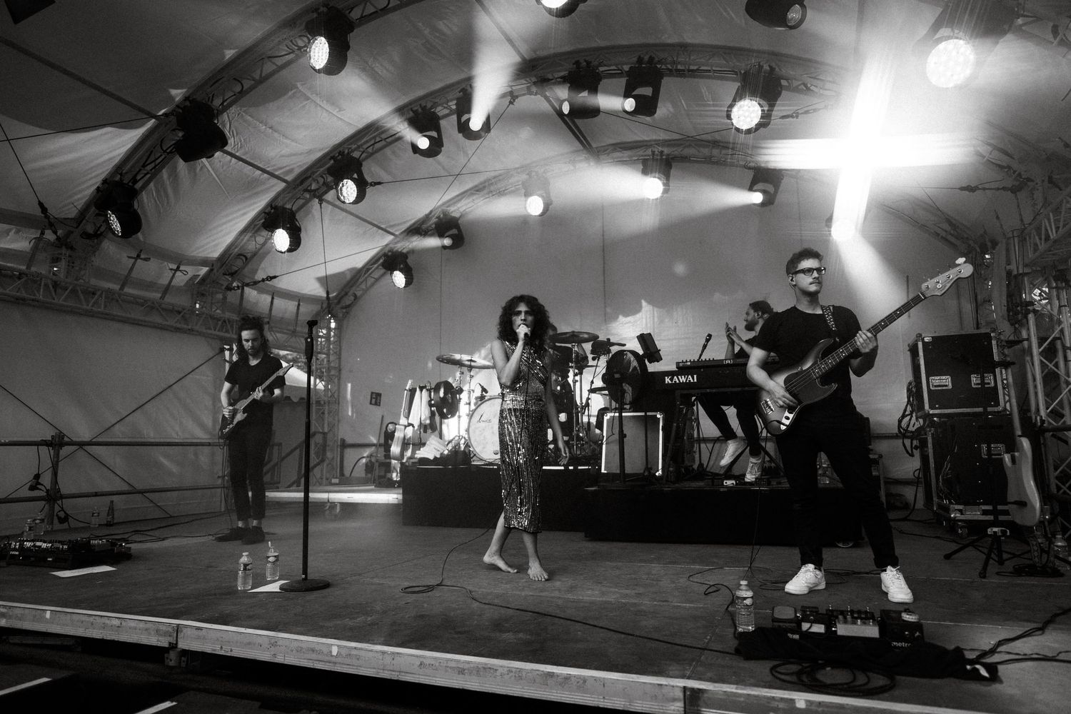 Wide shot of performers on stage in a tent venue with dramatic spotlighting.