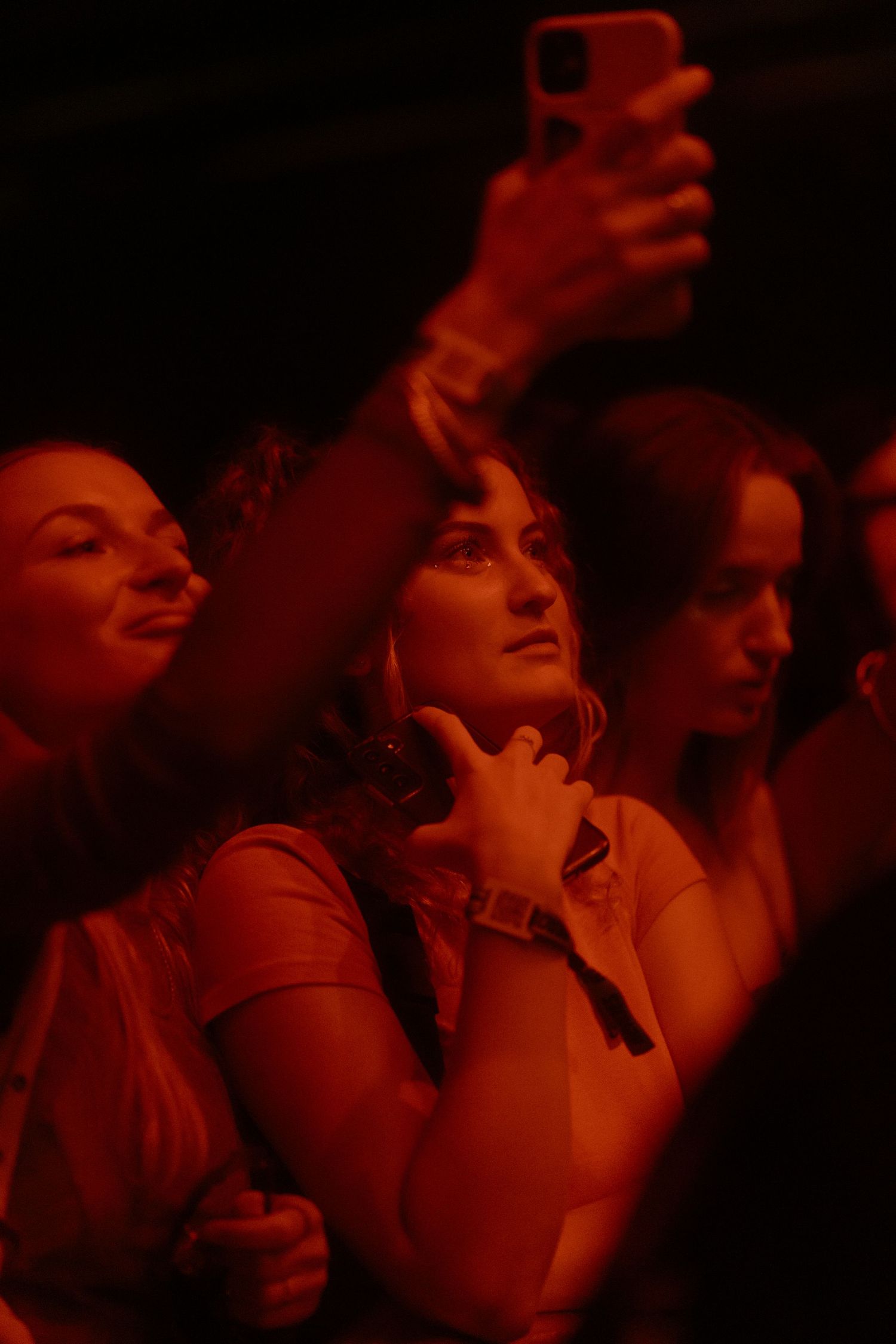 Concert audience bathed in dramatic red lighting during performance.