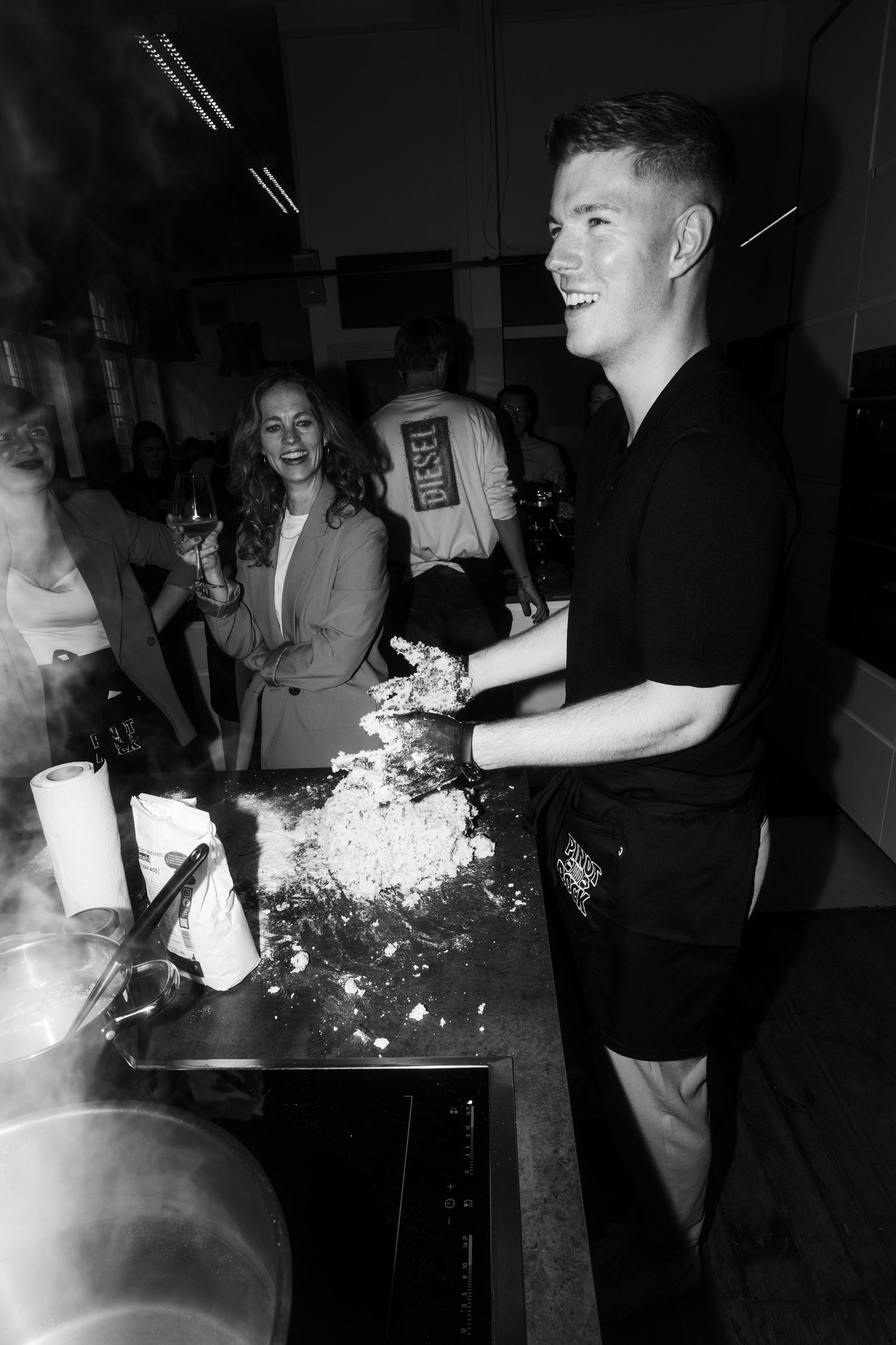 People gathered around a table with flour and cooking ingredients during a cooking class.