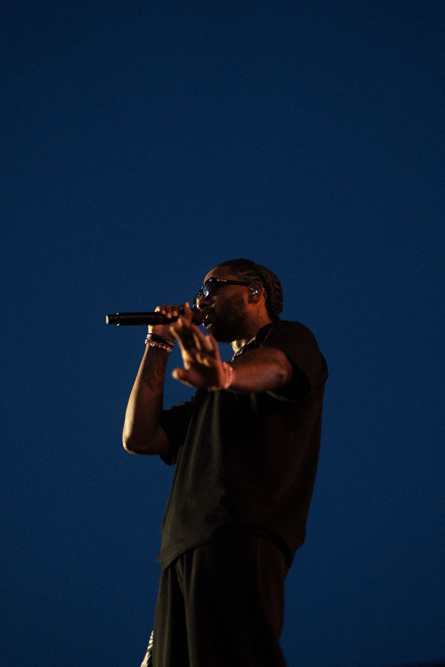 Reezy singing against deep blue background during concert performance.