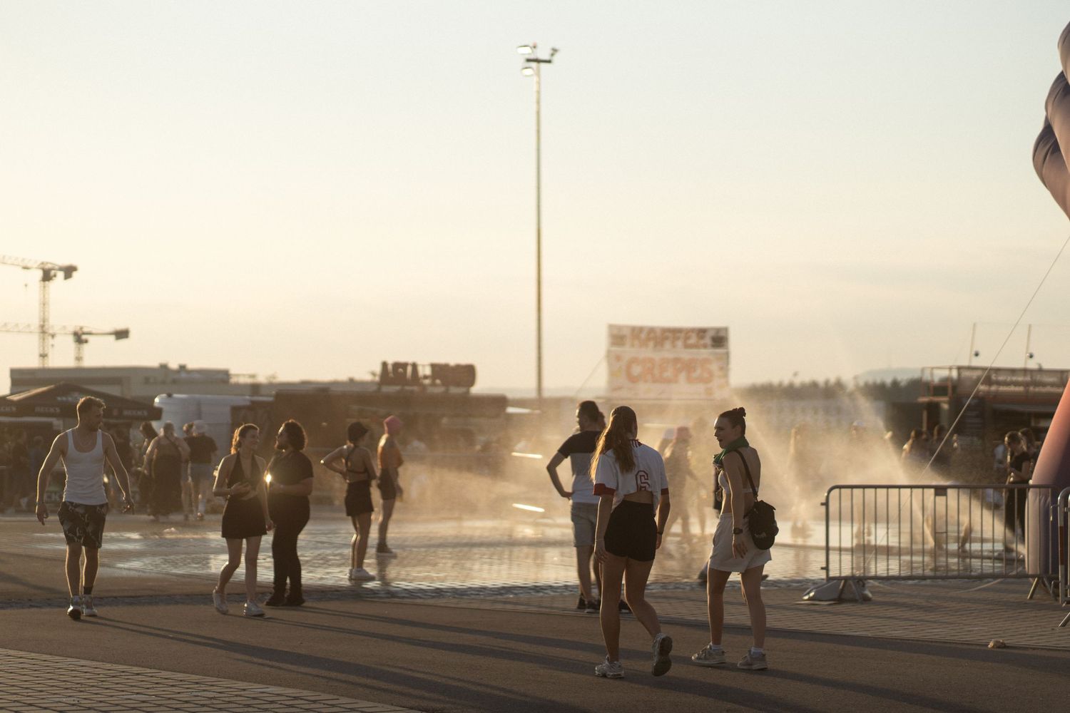 People walking through a sunlit parking lot at dusk.