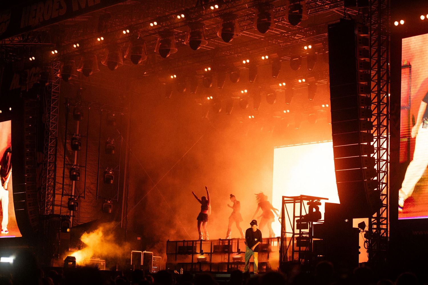 Concert stage illuminated with orange lighting and smoke effects.