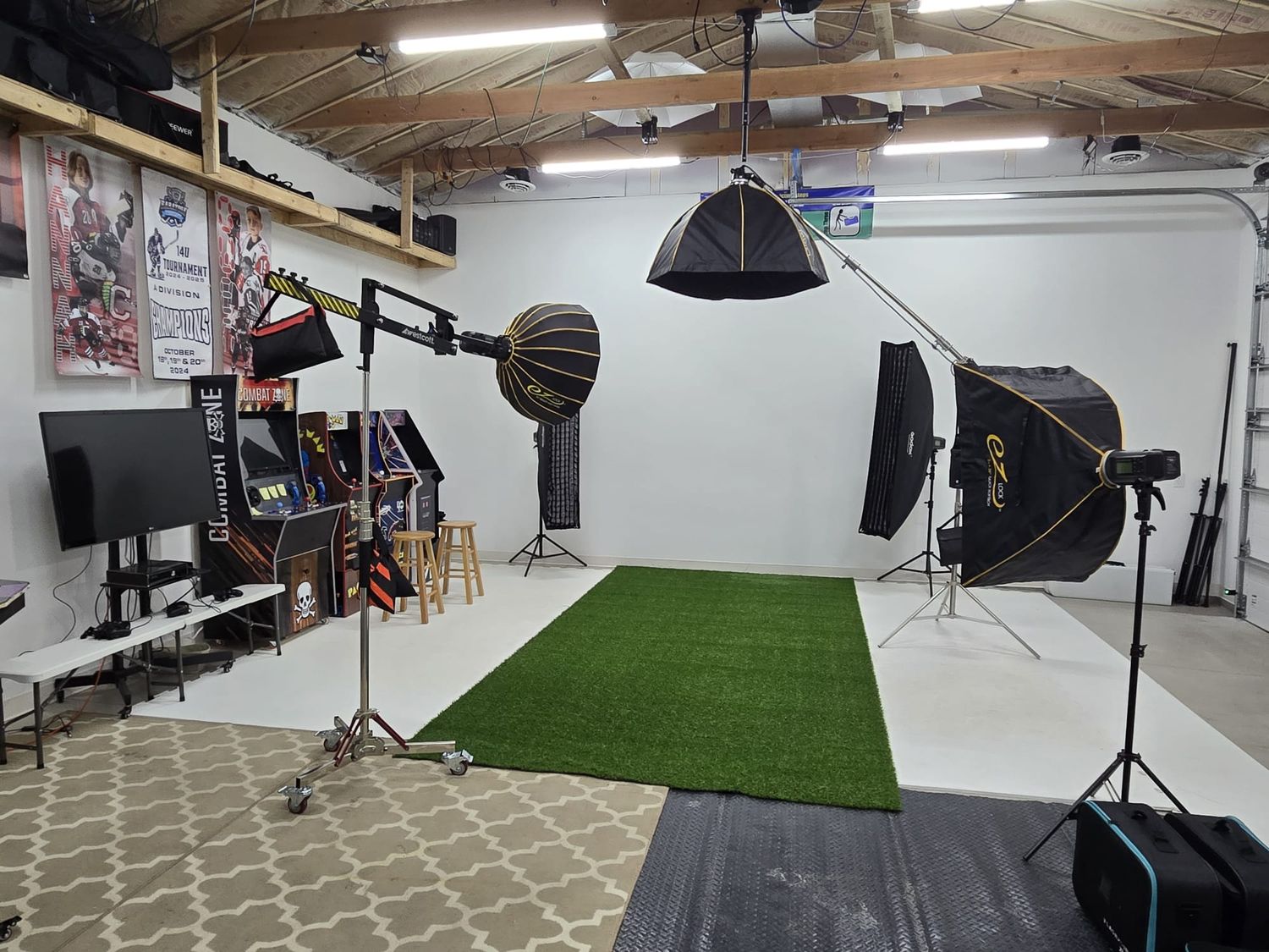 Large photography studio space with multiple shooting areas featuring artificial turf, professional lighting, and backdrop setups.