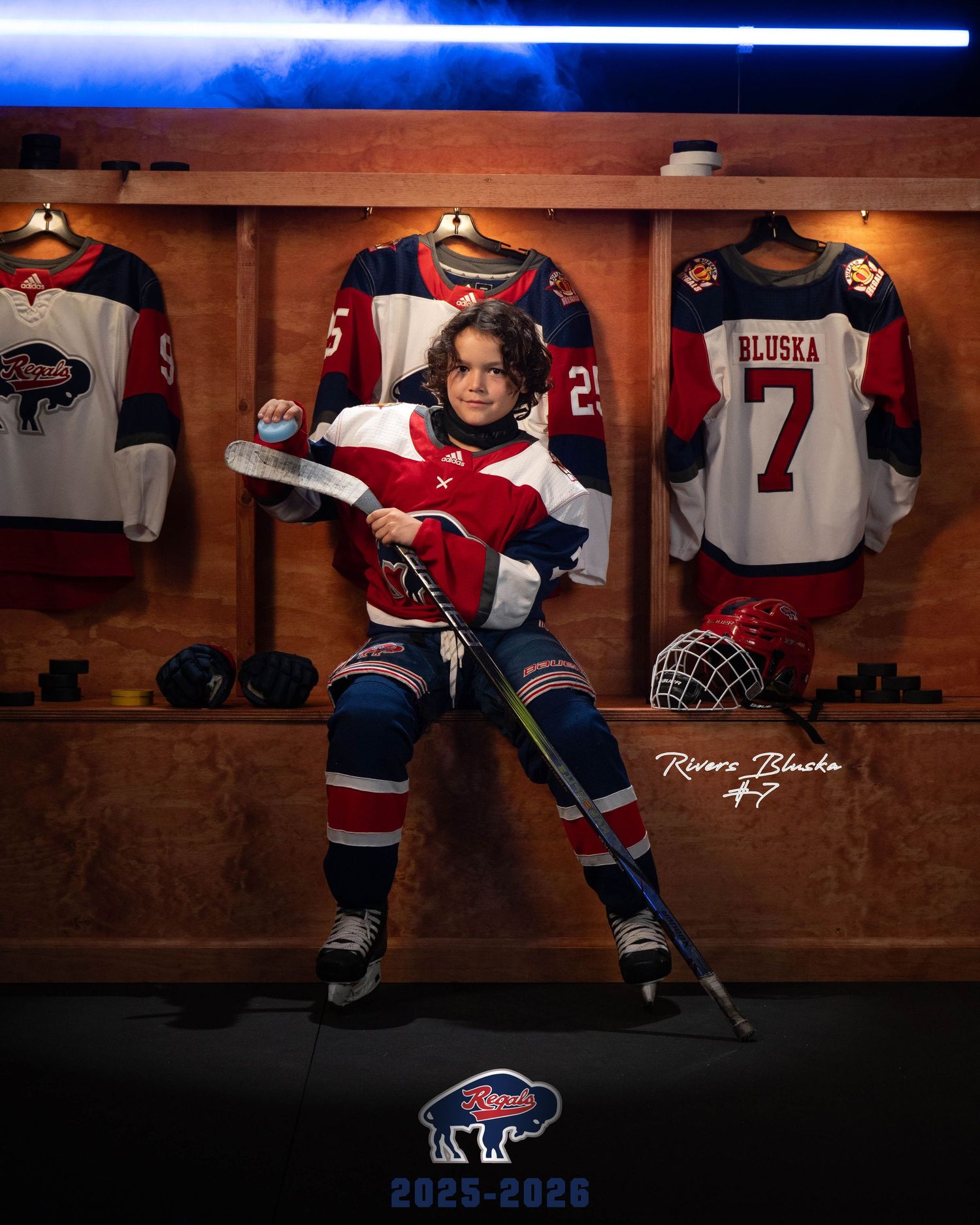 Hockey players in blue and red jerseys sit in a wooden locker room displaying equipment and uniforms.
