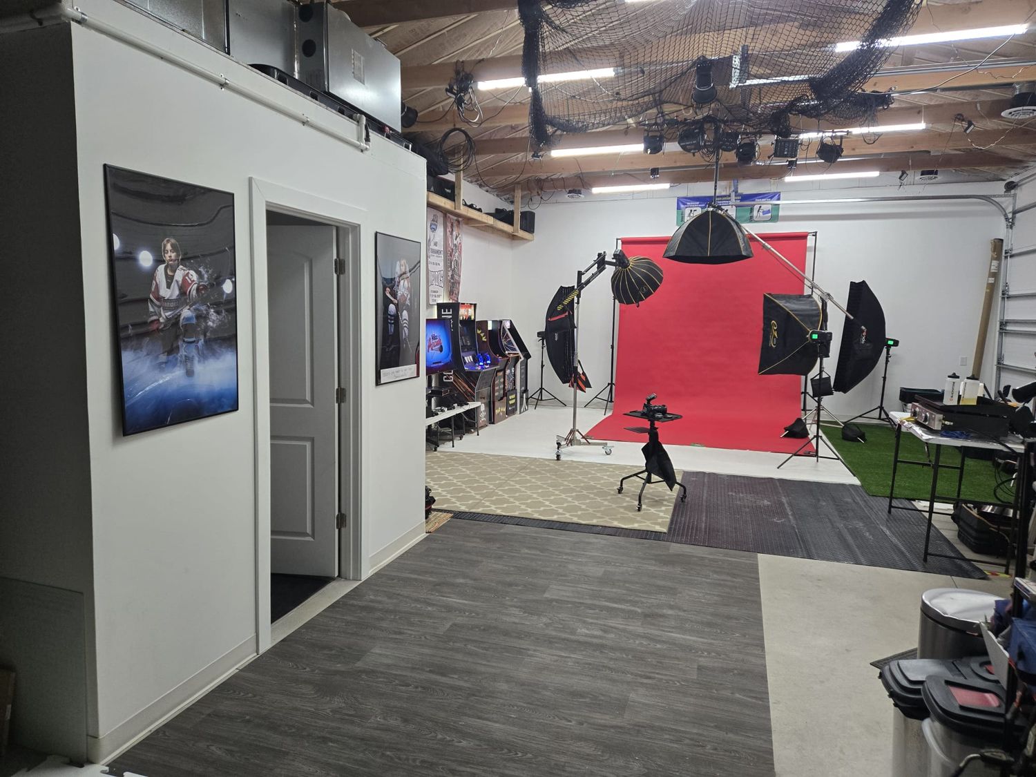 Professional photography studio interior with red backdrop setup, lighting equipment, and gray flooring in an industrial space.