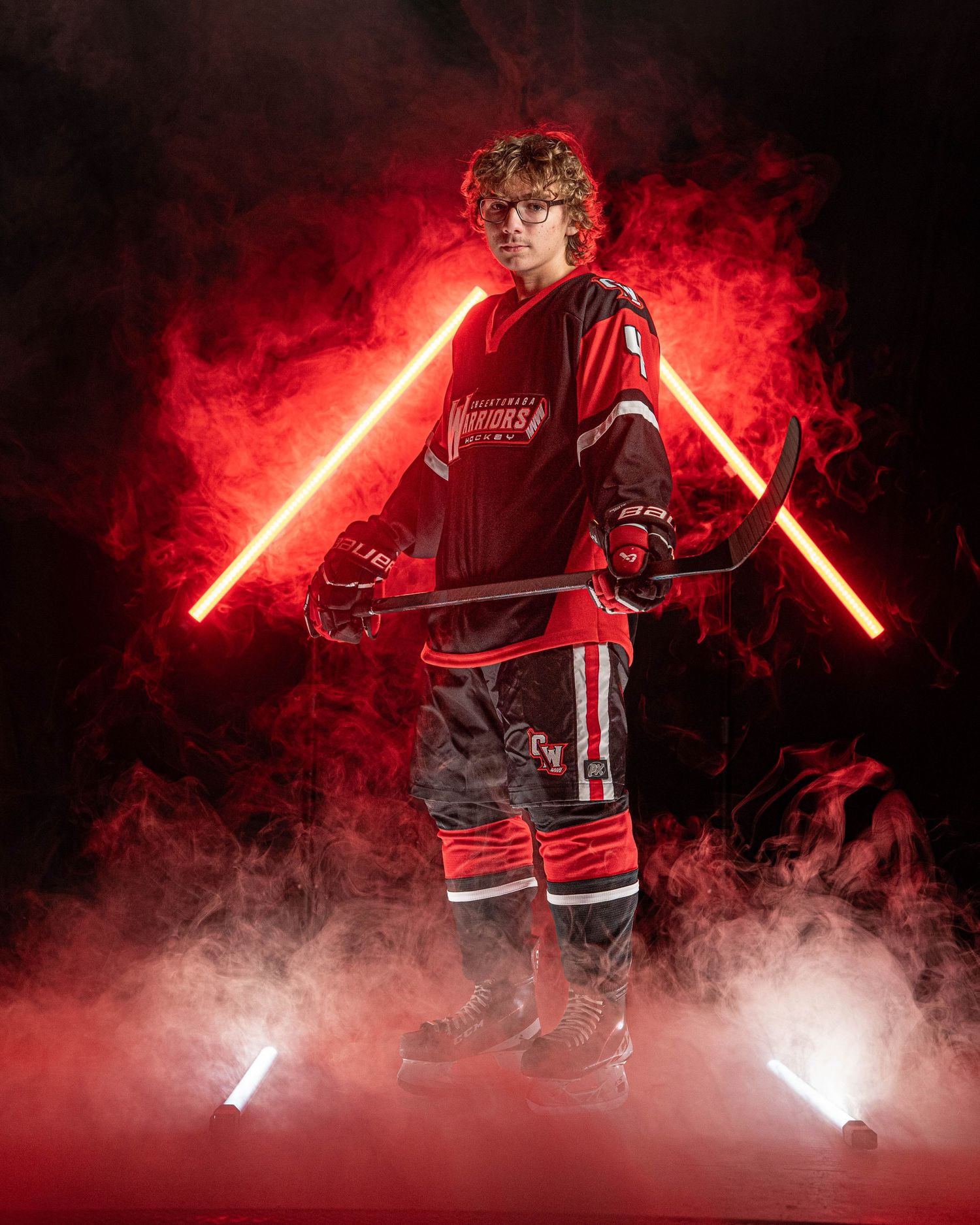 Athletic figure stands dramatically in red hockey uniform with glowing lightsabers amidst smoky atmosphere.