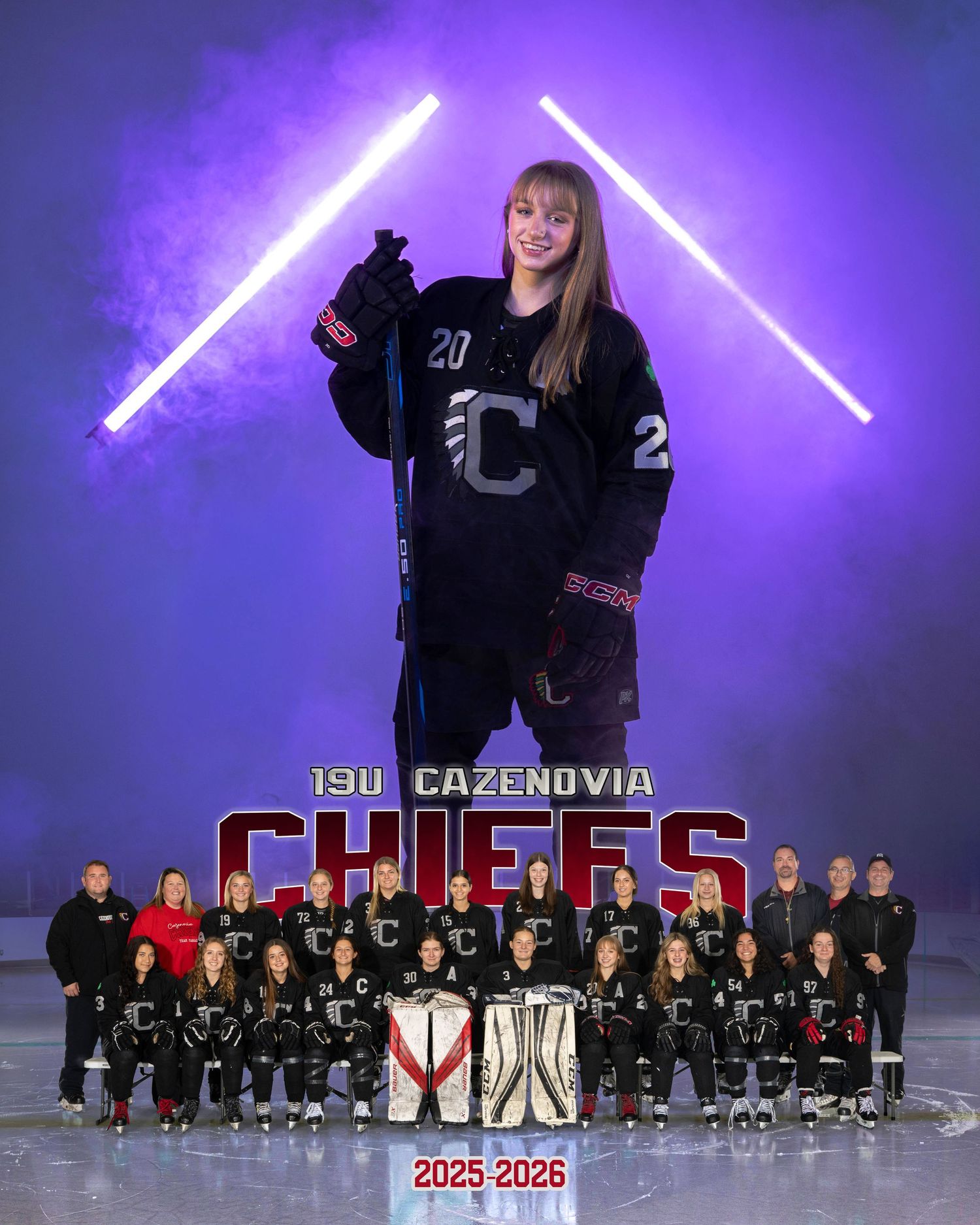 High school hockey team poses in black jerseys against a dramatic purple-lit backdrop for their official team photo.