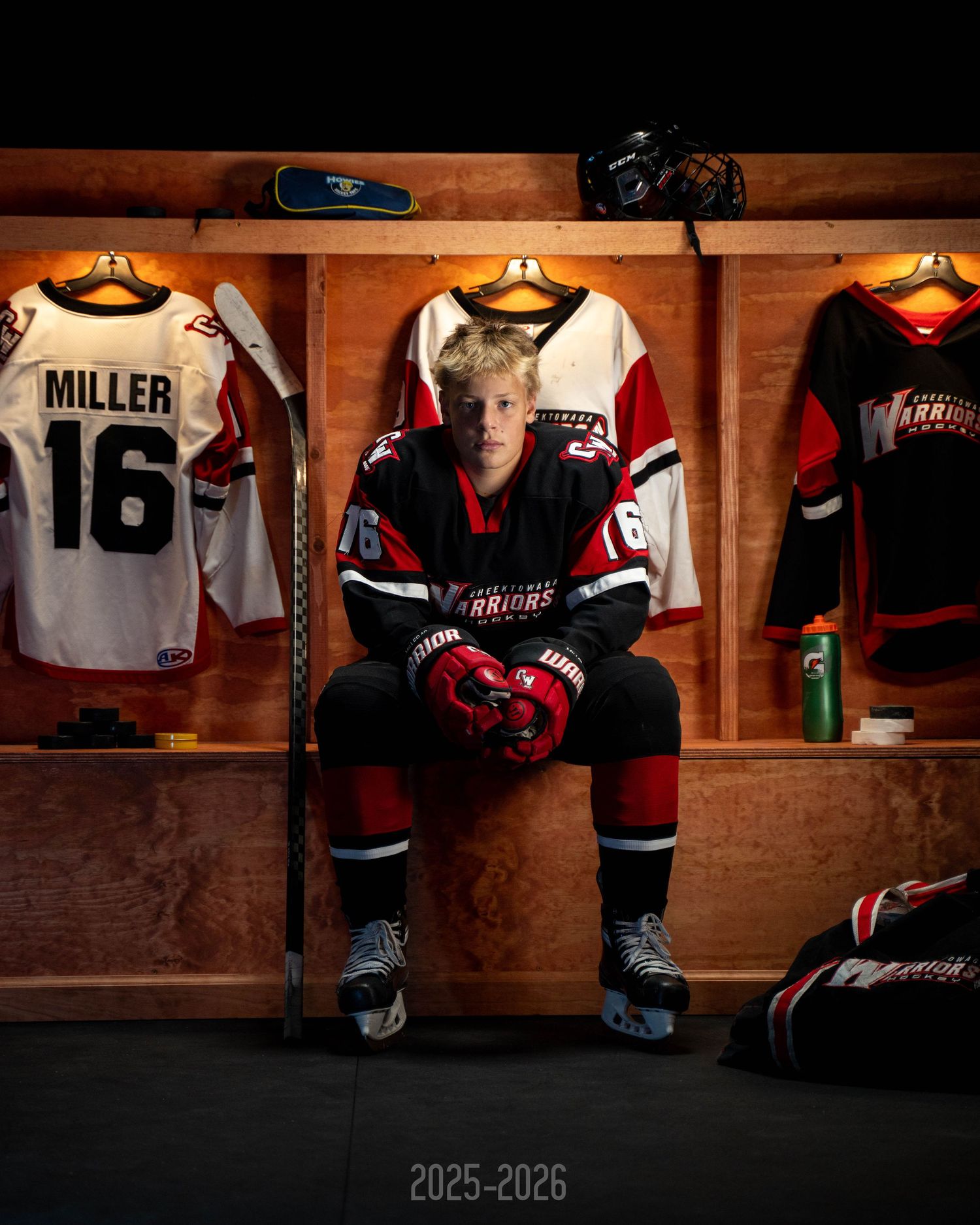 Multiple hockey jerseys and gear hanging in wooden lockers in a rustic sports locker room setting.