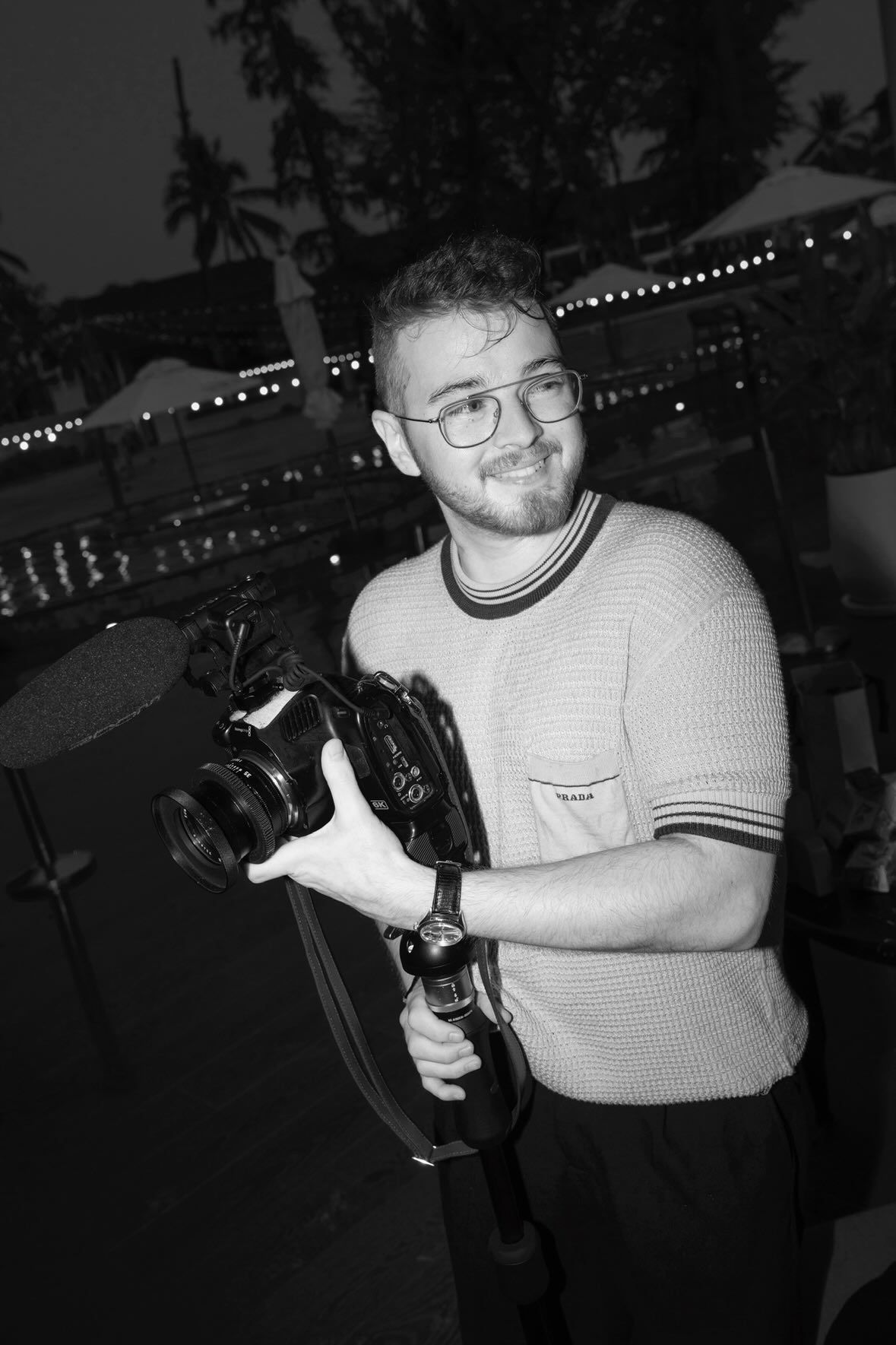 Black and white candid shot of Tobi filming with his camera, capturing a moment during a wedding day.