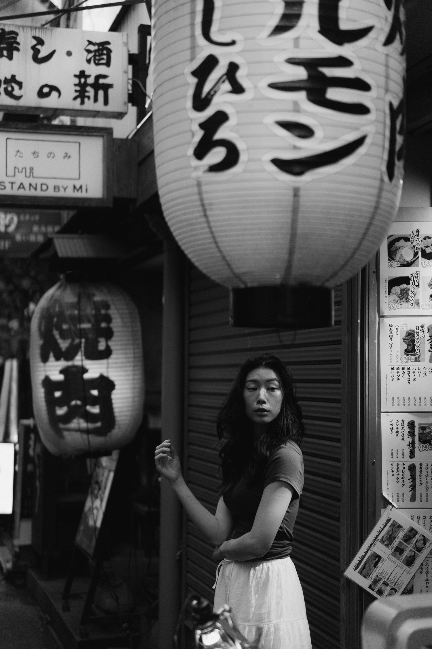White Japanese lanterns with kanji characters illuminate a traditional market street at night.