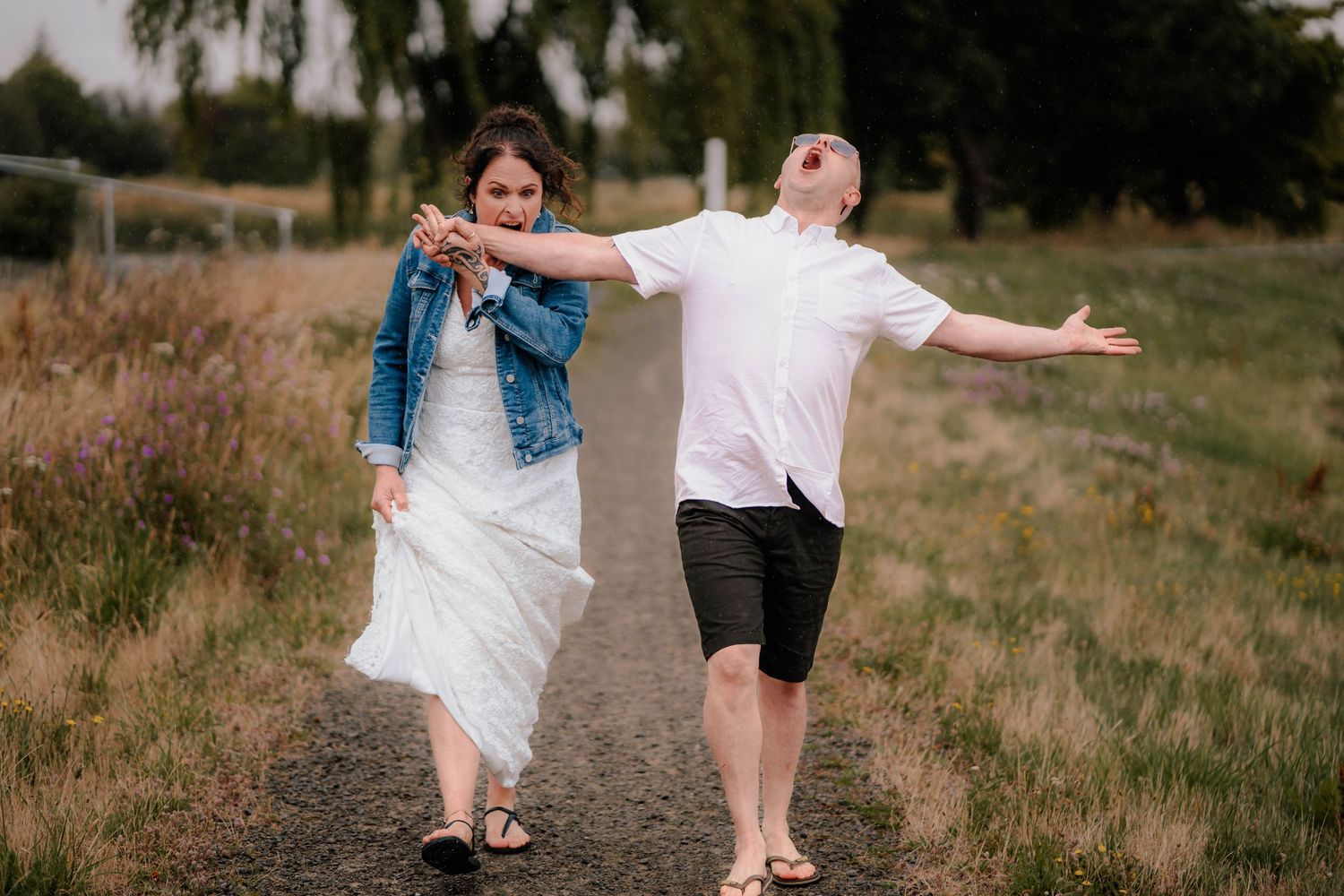 Two people enjoying a fun moment together on a rustic path through a grassy meadow area.