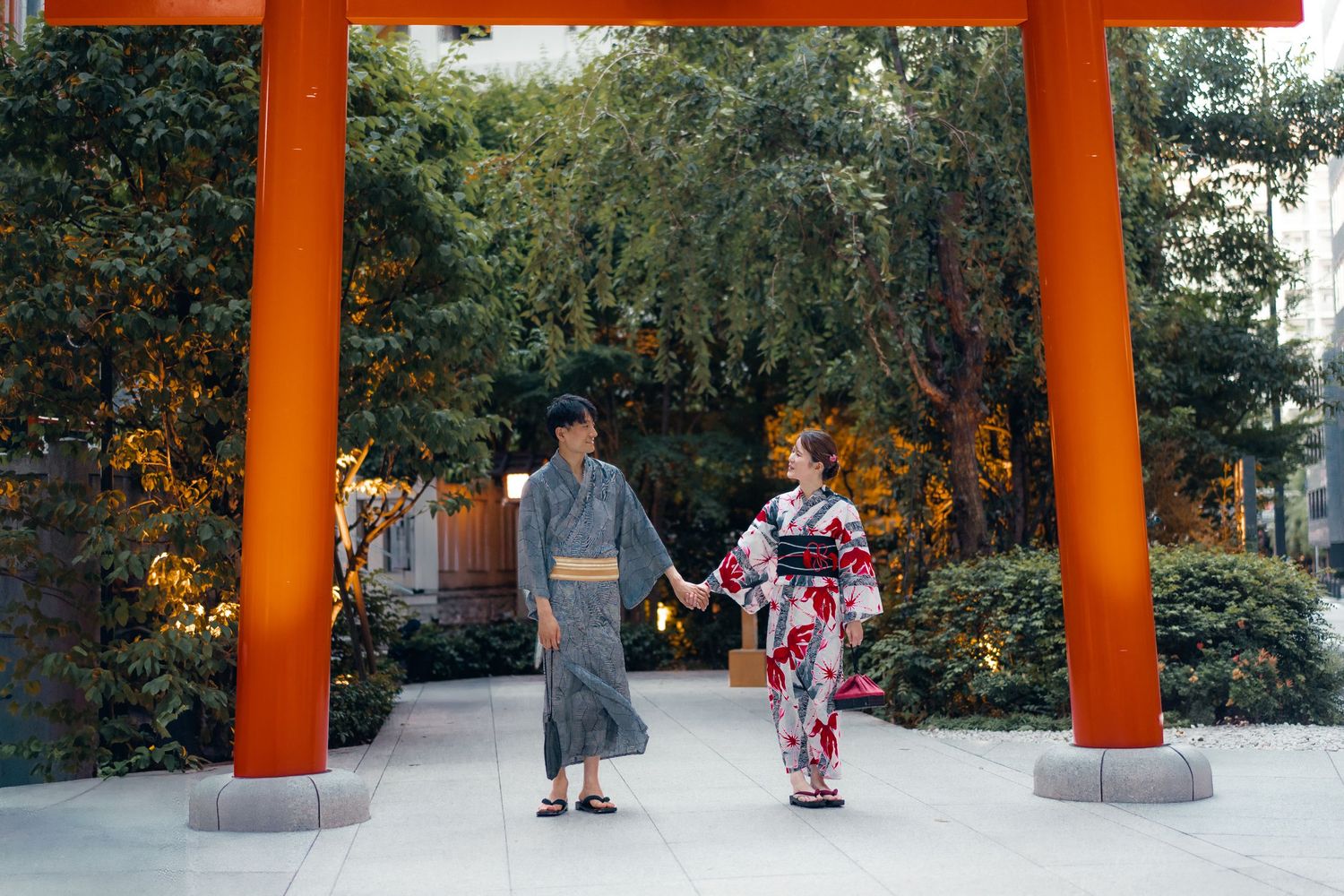 People strolling beneath bright orange torii gates along a stone path at a Japanese shrine.