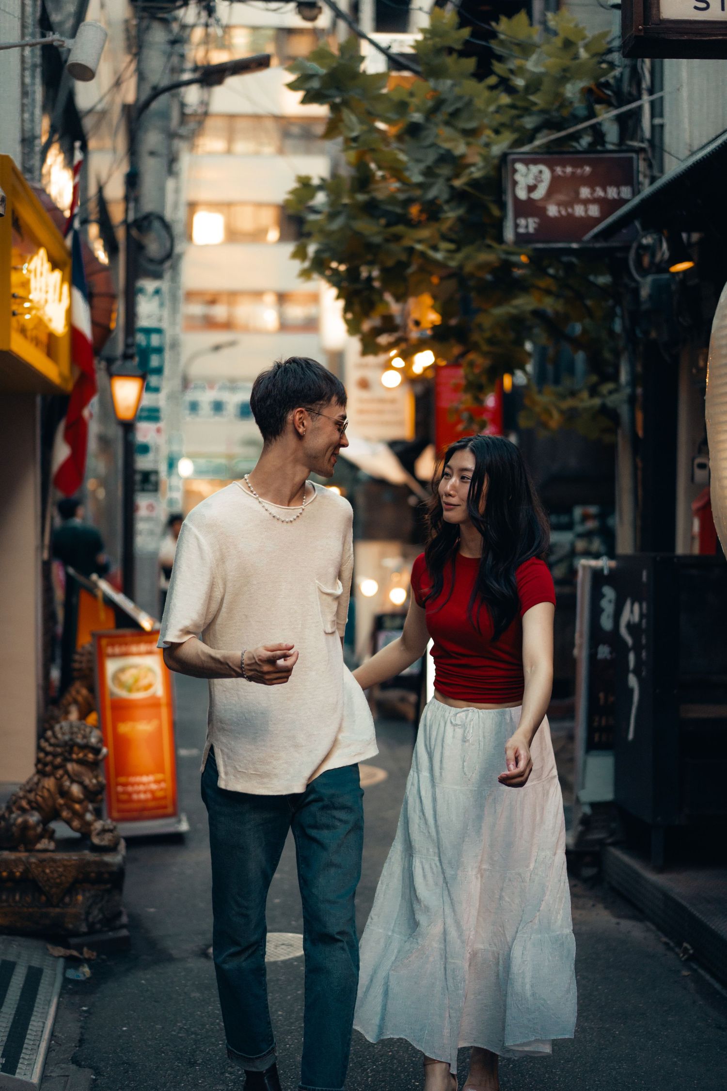 Two people walking together on a city street in casual attire during late afternoon light.