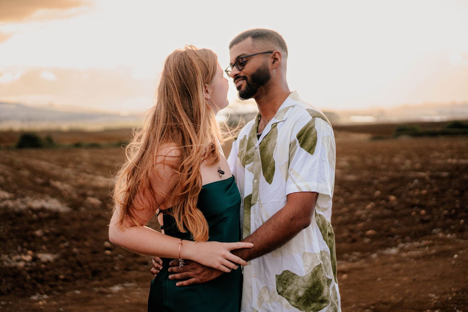 A couple poses together against a scenic desert landscape during sunset creating a romantic silhouette.