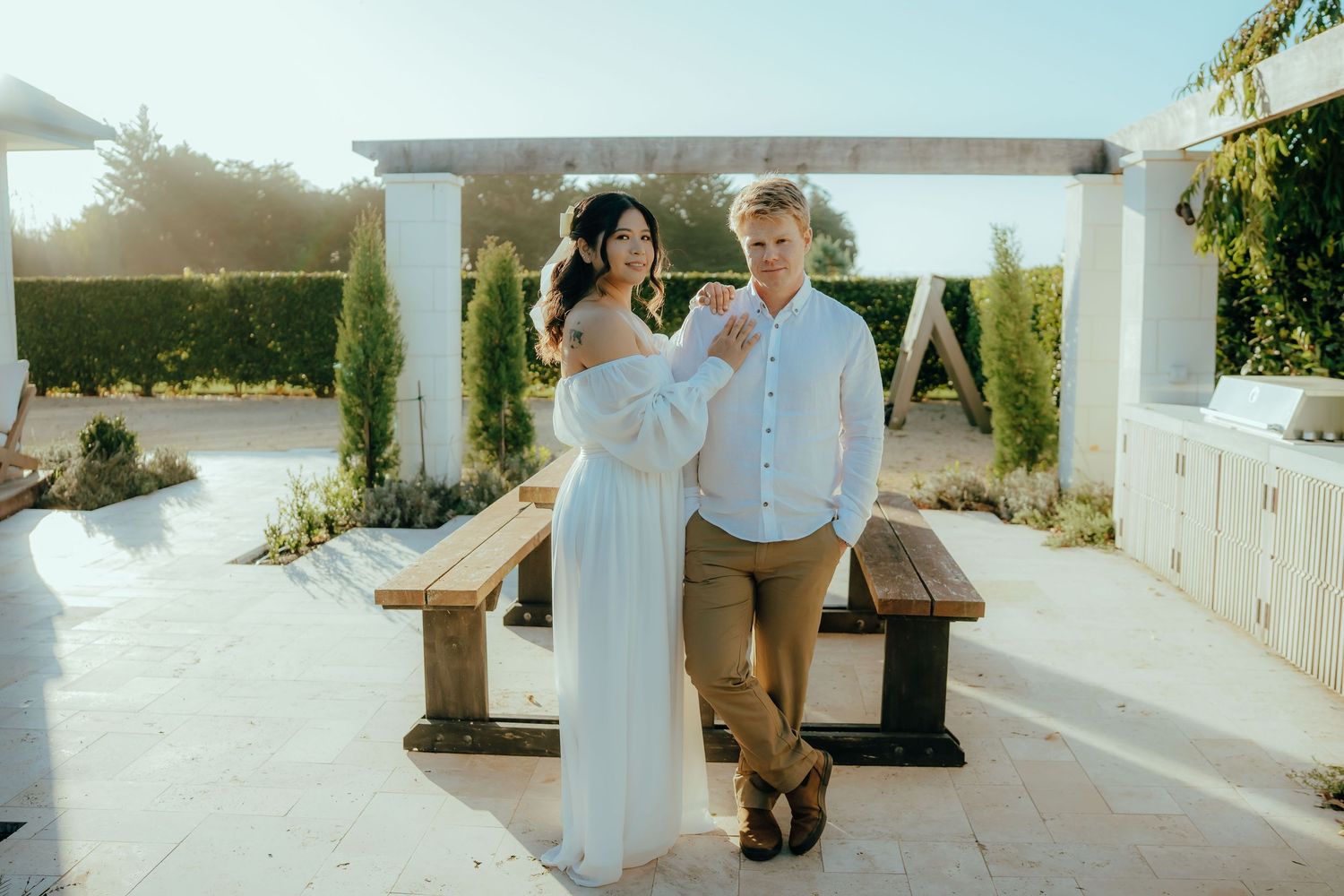 A romantic outdoor garden wedding ceremony features a happy couple surrounded by white columns and natural decor.