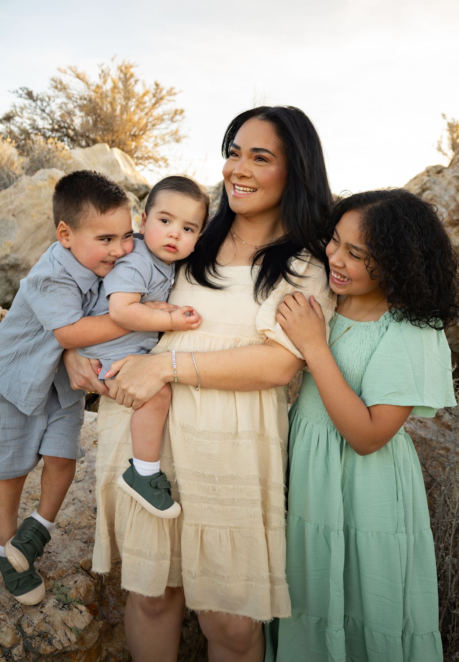 family photos at antelope island in utah. Mom and her 3 kids are hugging eachother and smiling in a joyous moment together. lifestyle photos