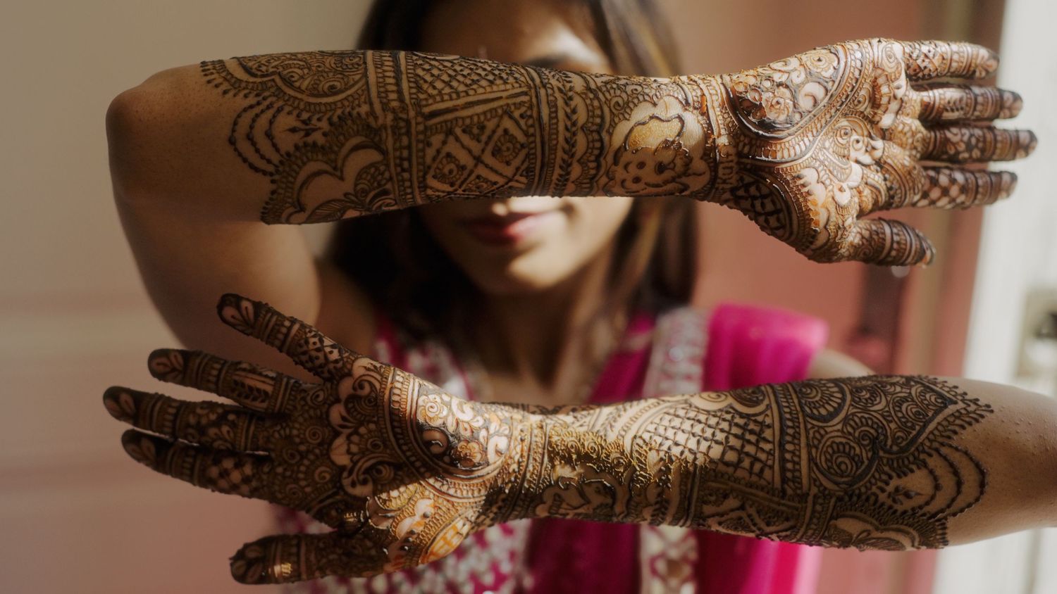 Detailed henna designs on hands displayed against a neutral background.