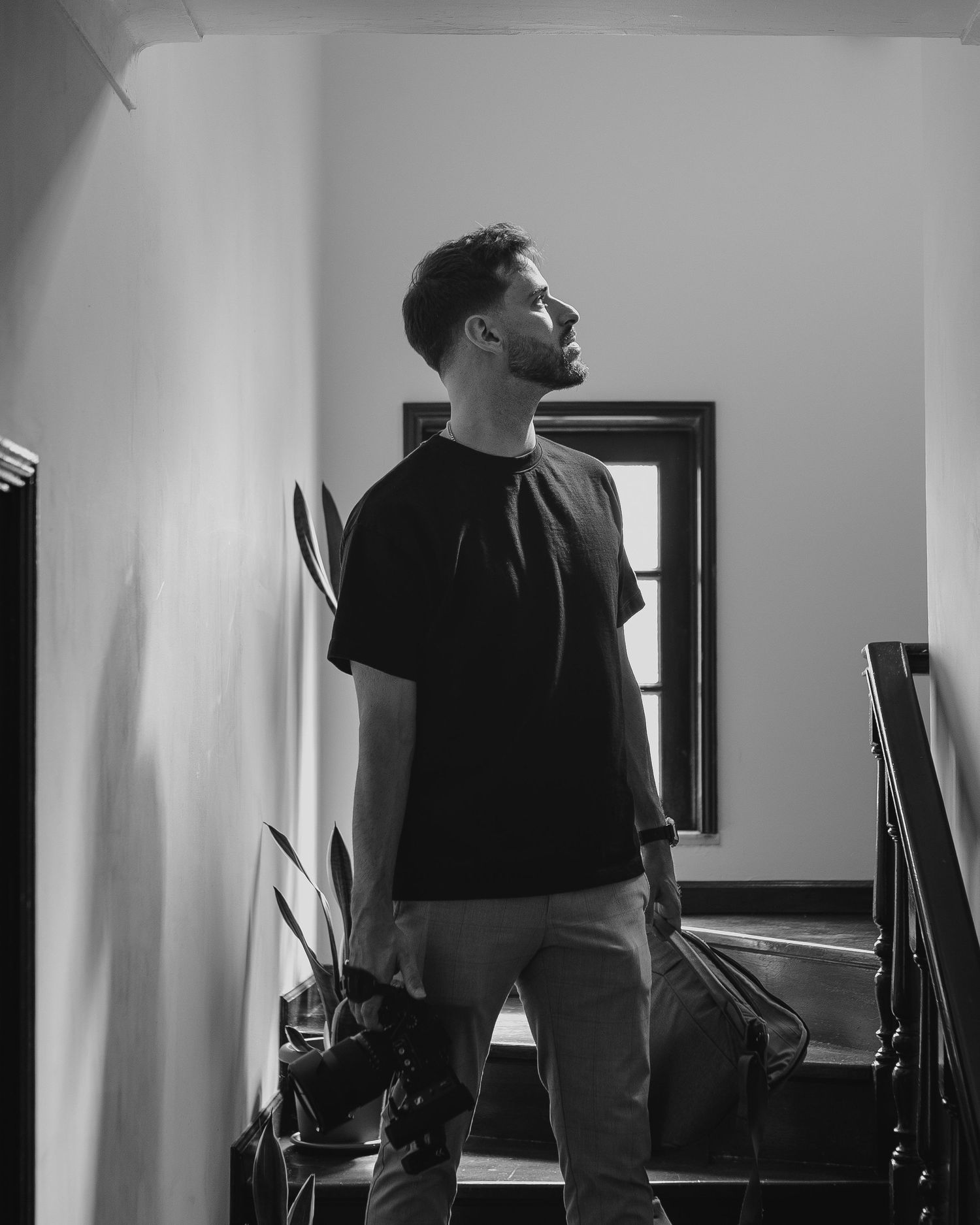 Monochrome image of a figure standing by a window in stark contrast.
