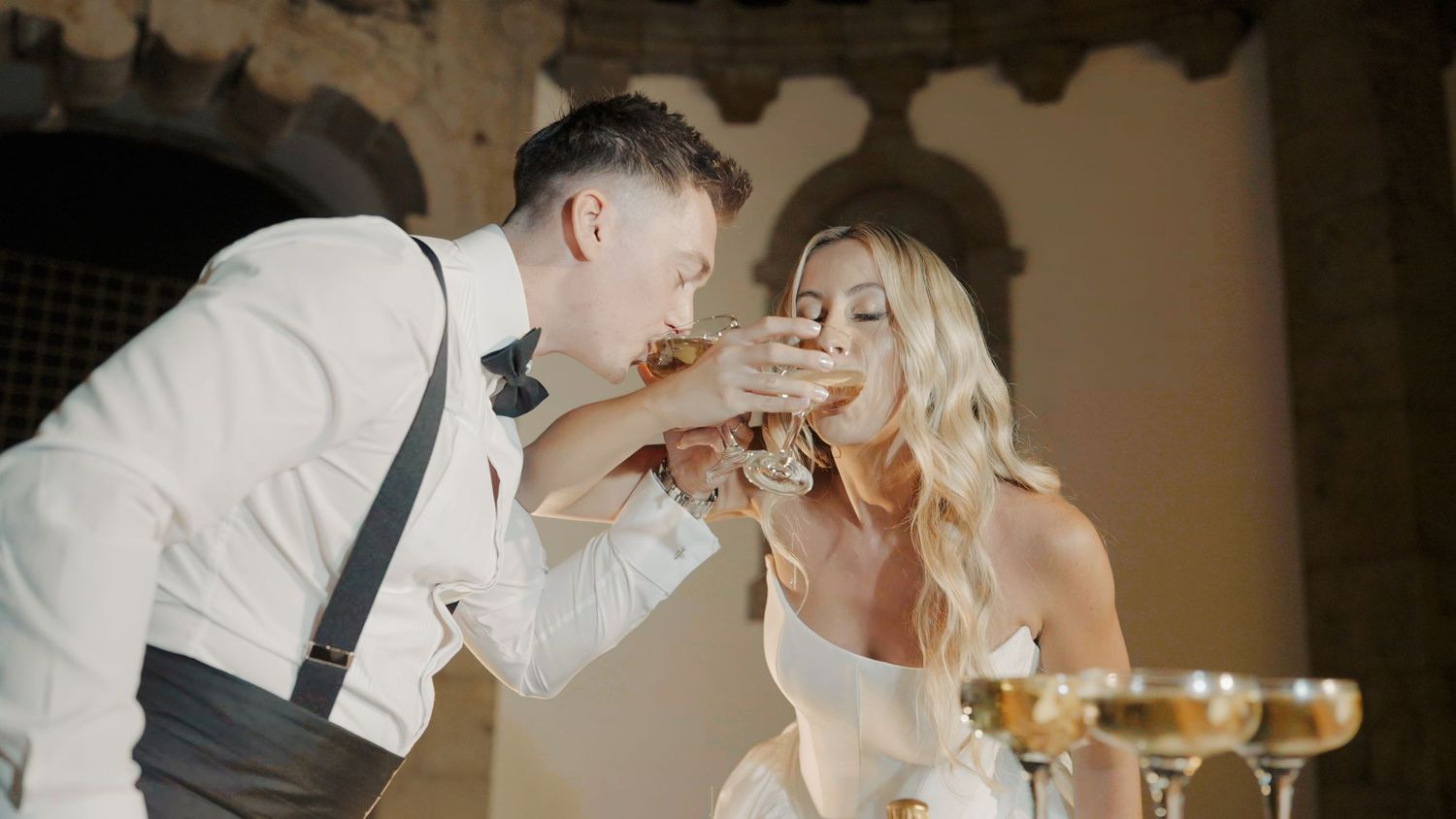 A wedding celebration scene with glowing candles and wine glasses creating an intimate atmosphere.