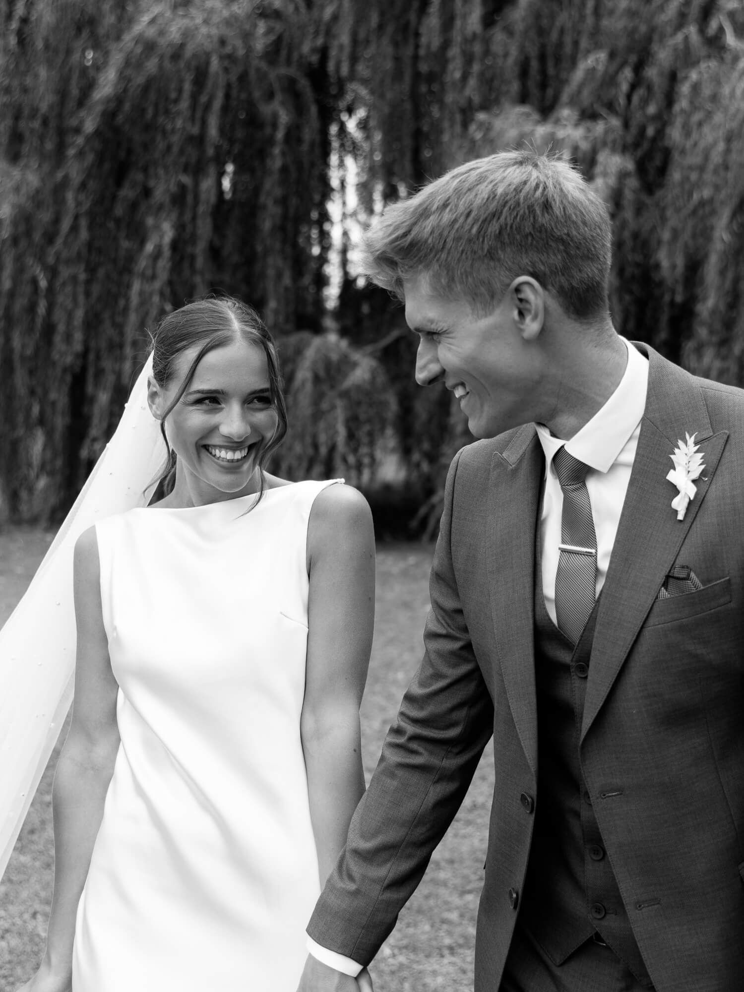 A happy couple in formal attire share candid laughs and smiles in a series of black and white wedding photos.