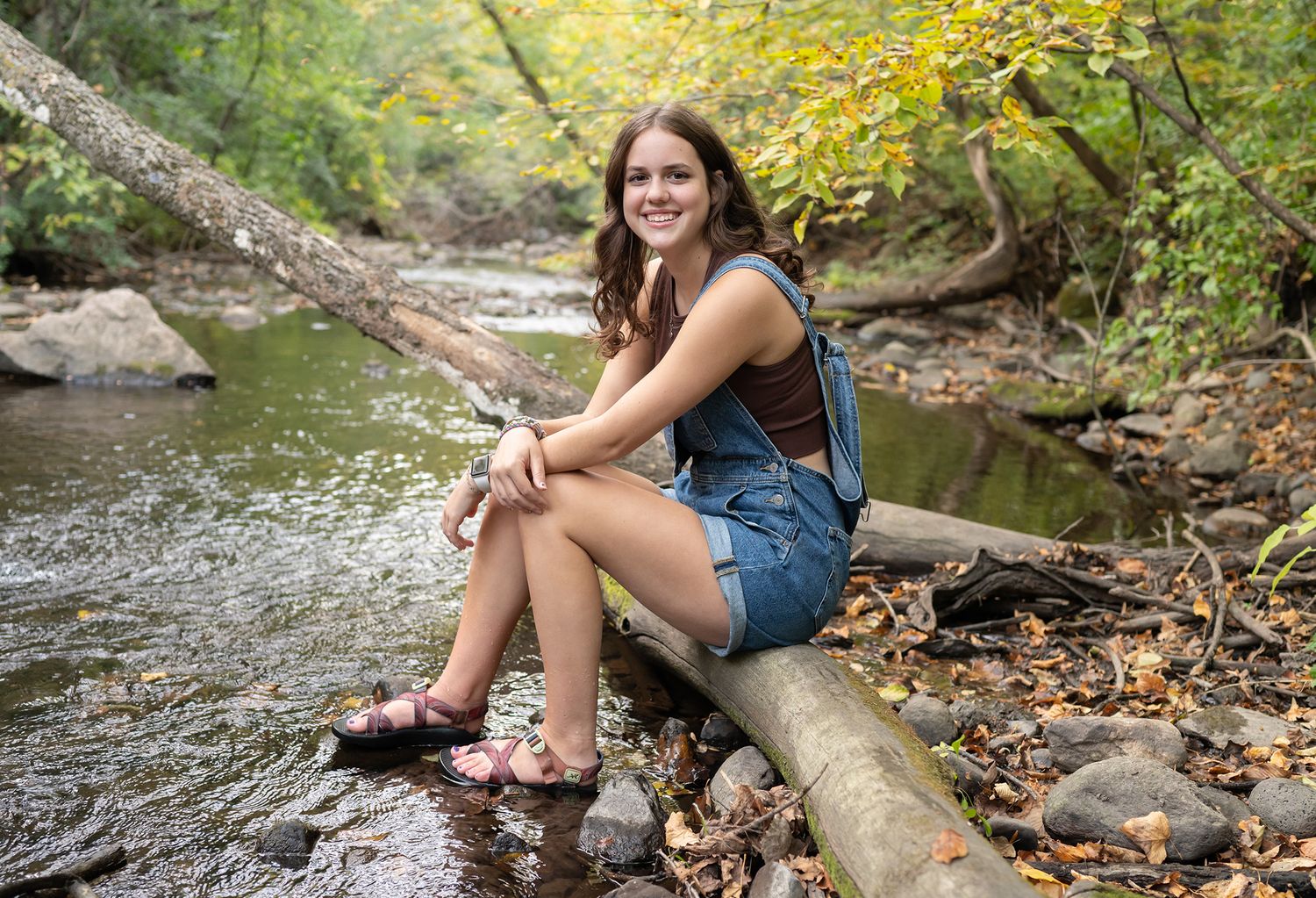 high school senior girl in creek water rocks