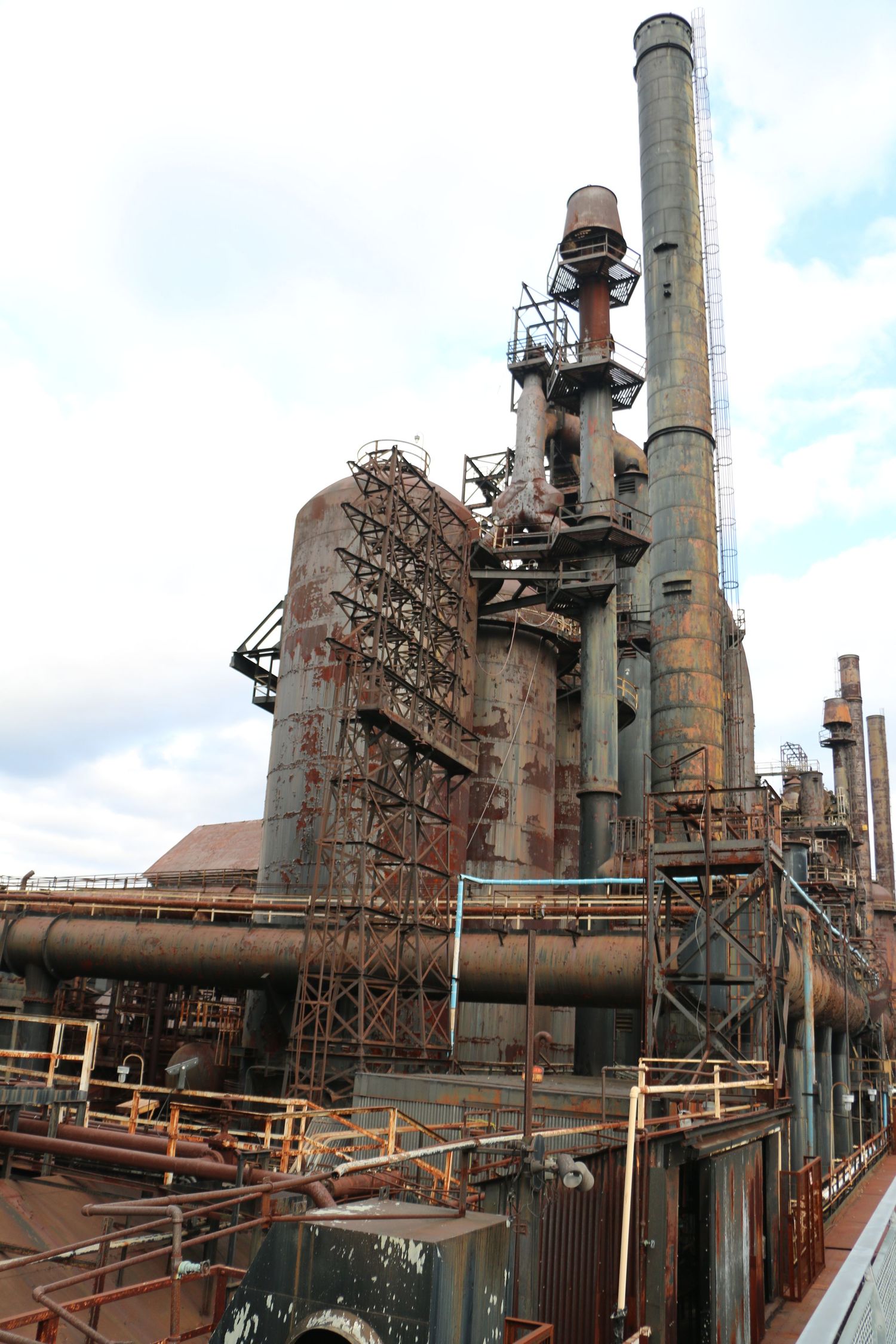 Rusty abandoned steel mill blast furnace with industrial smokestacks against cloudy sky at Bethlehem Steel site.