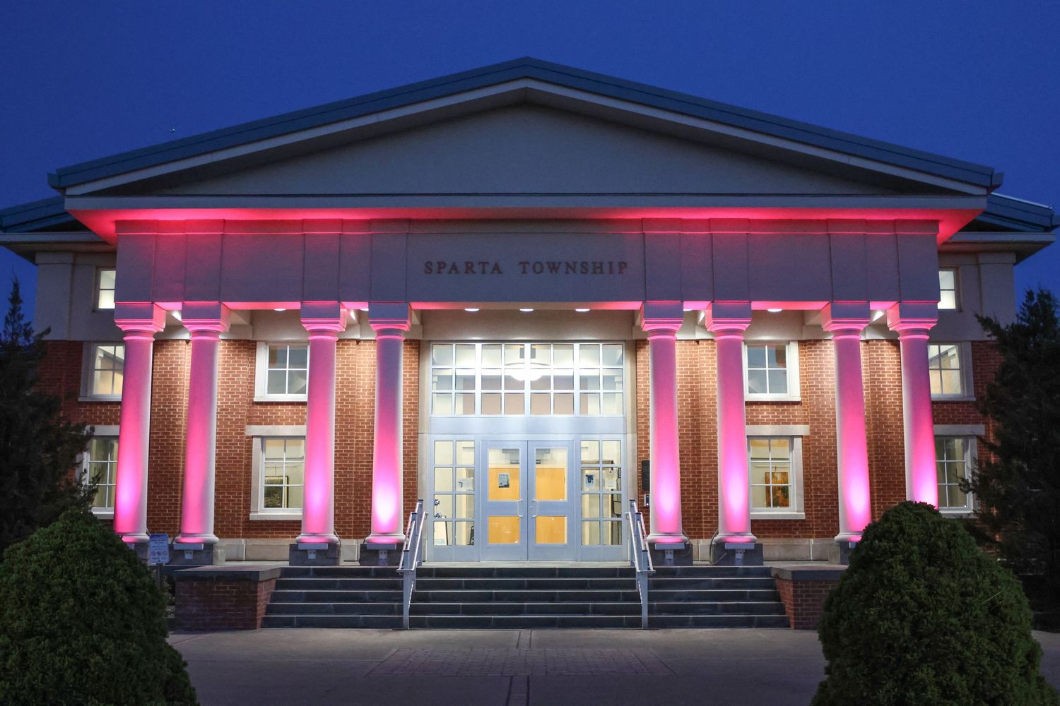 Sparta Township building illuminated with pink lights at night.